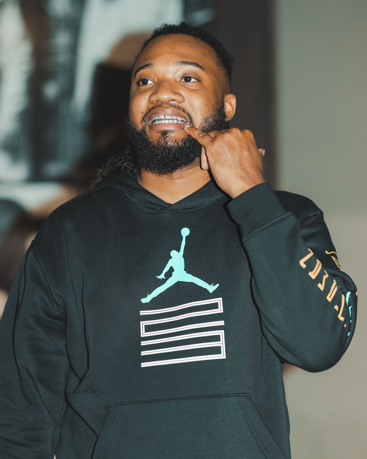 Person wearing black Jordan hoodie with light blue logo in indoor setting.