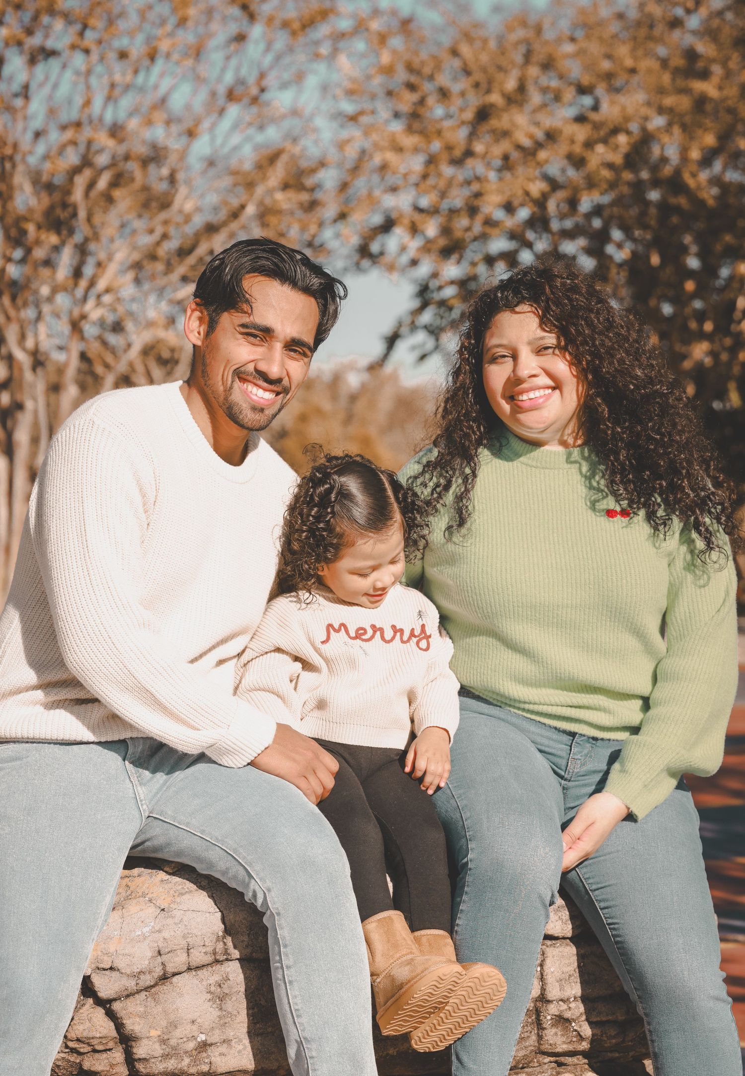 Candid autumn family photoshoot with warm tones and fall foliage in the background.