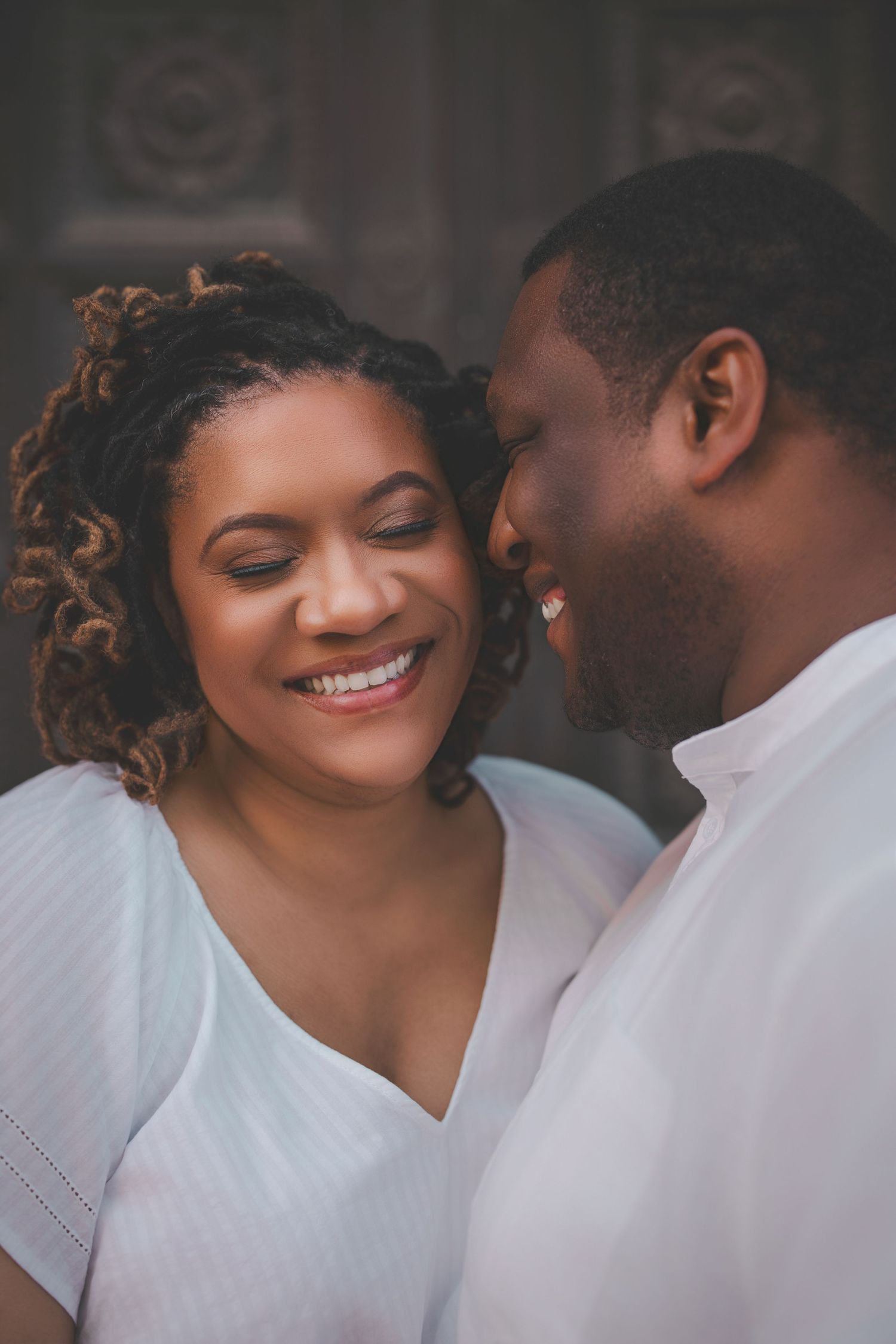 A couple shares tender moments while wearing coordinated white outfits during a photo session.