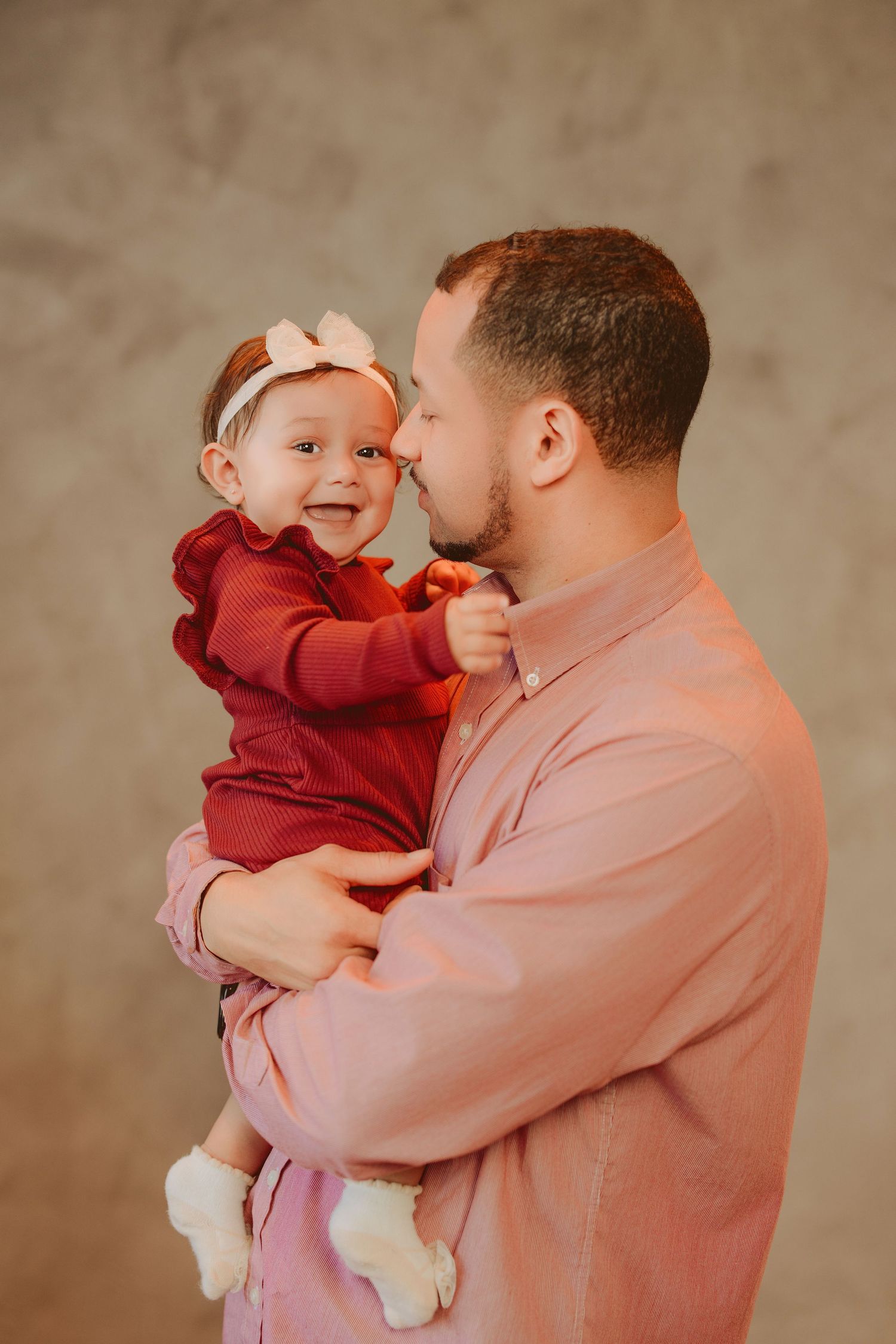 Sweet candid moment between parent and baby in matching pink and burgundy outfits.