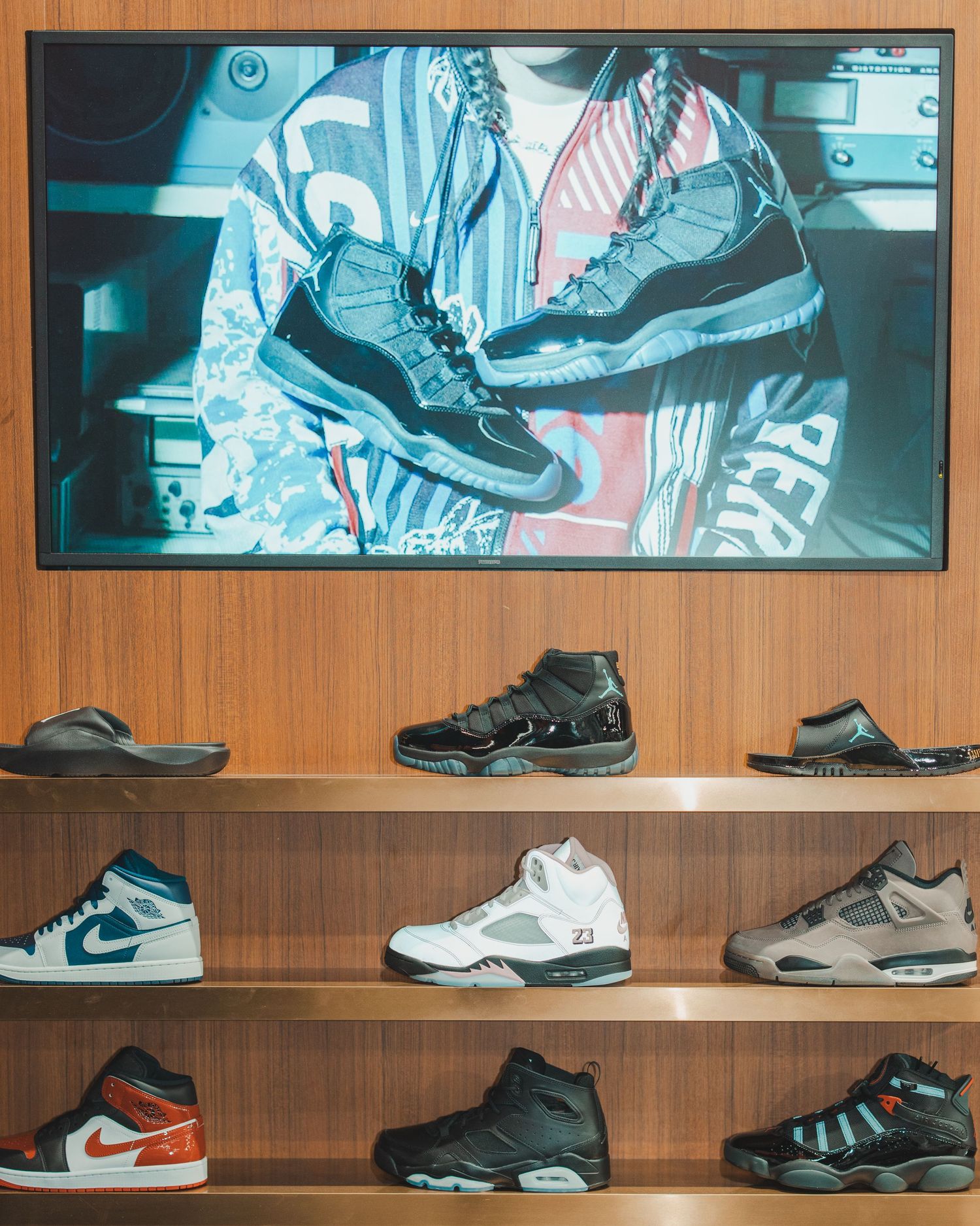Display of classic sneakers arranged on wooden shelves with backlit panels showing shoe designs.