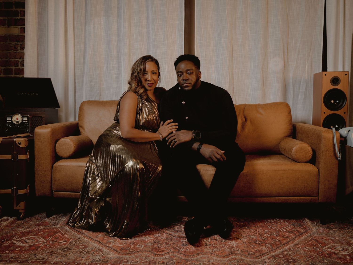 Romantic couple lounges on tan couch during intimate indoor photoshoot session.