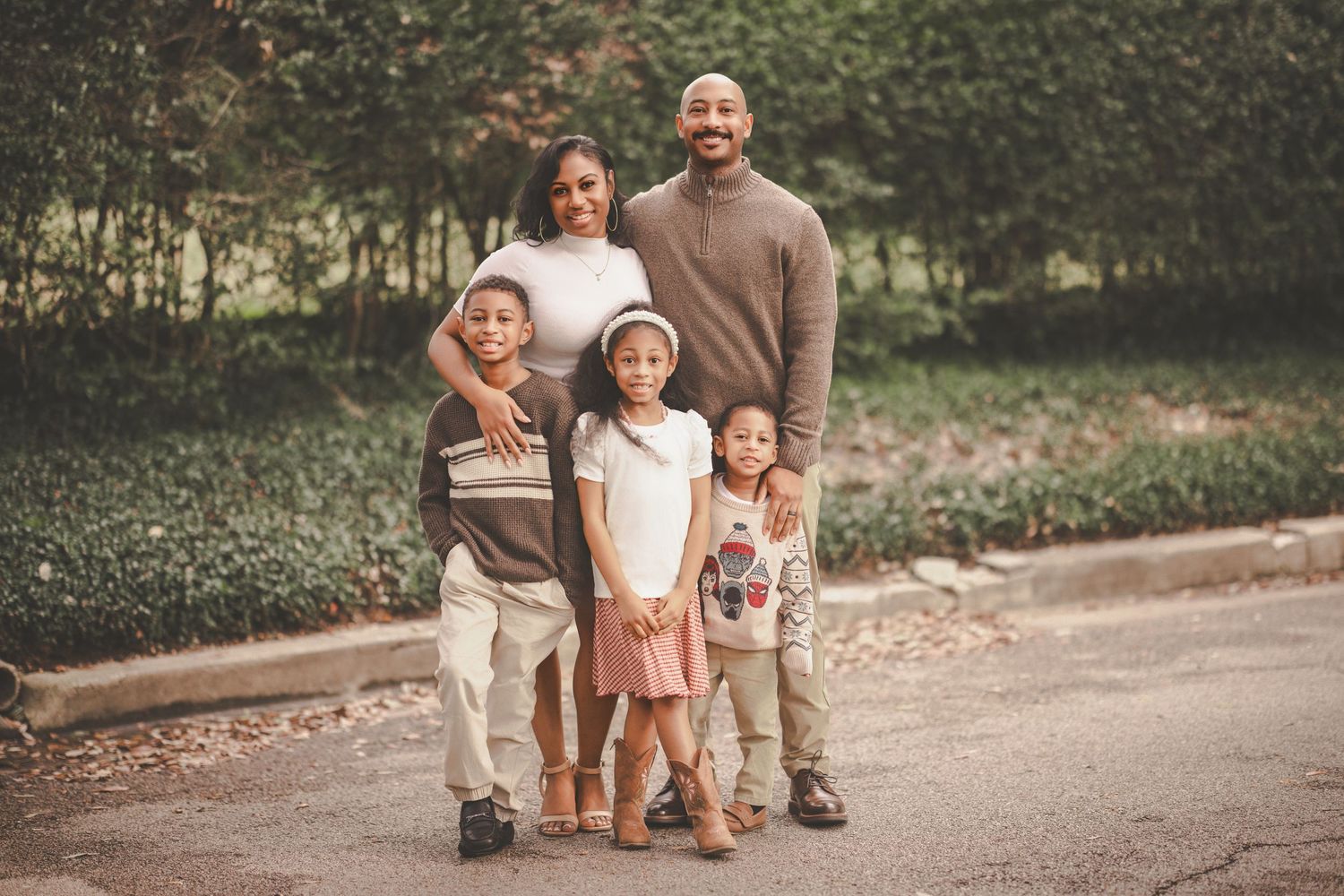 A family walks together on a wooded path during a fall afternoon photo session.
