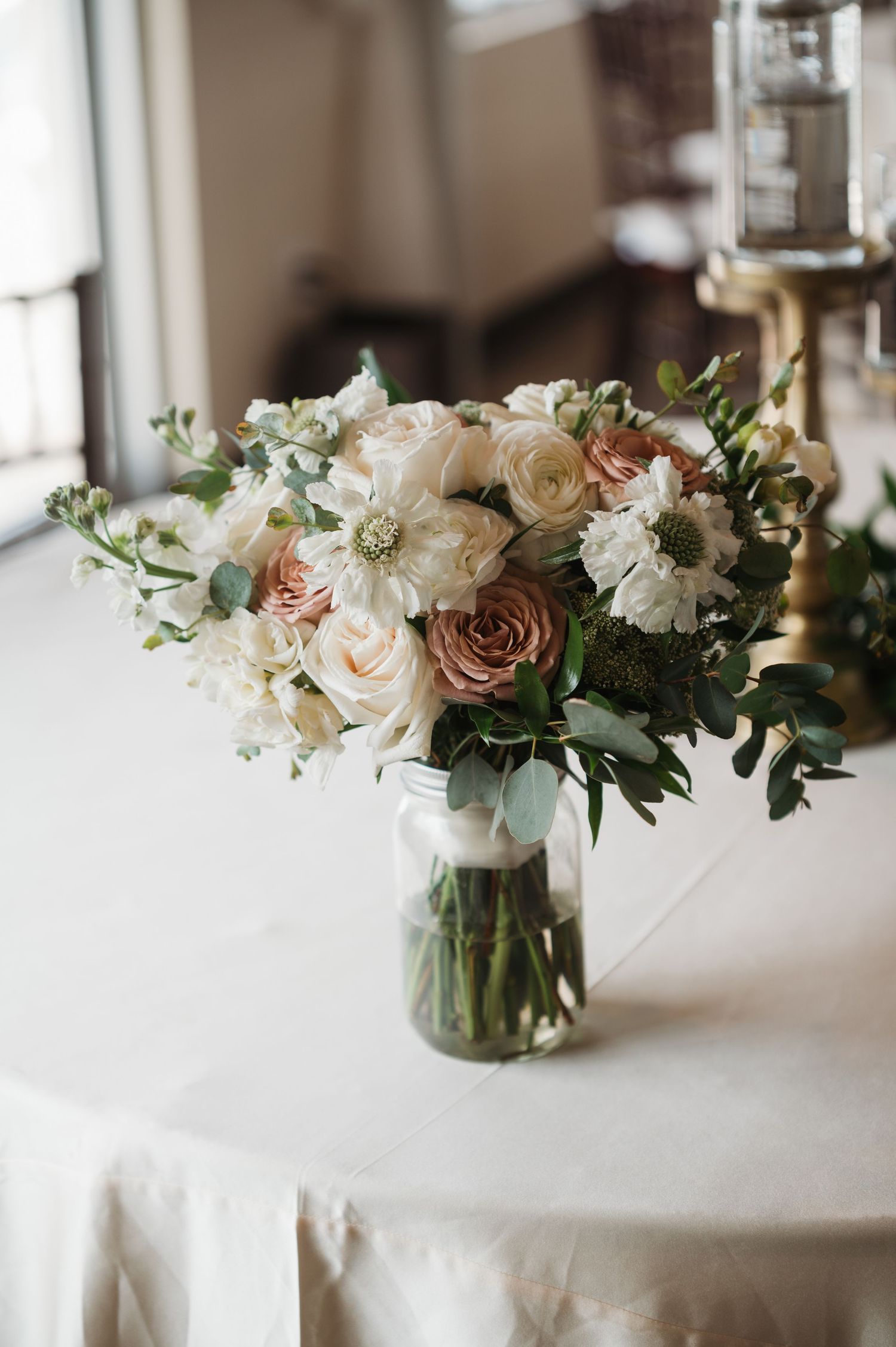 Elegant wedding bouquet of white, cream, and dusty rose roses in glass vase on table. Corpus Christi Wedding Photographer