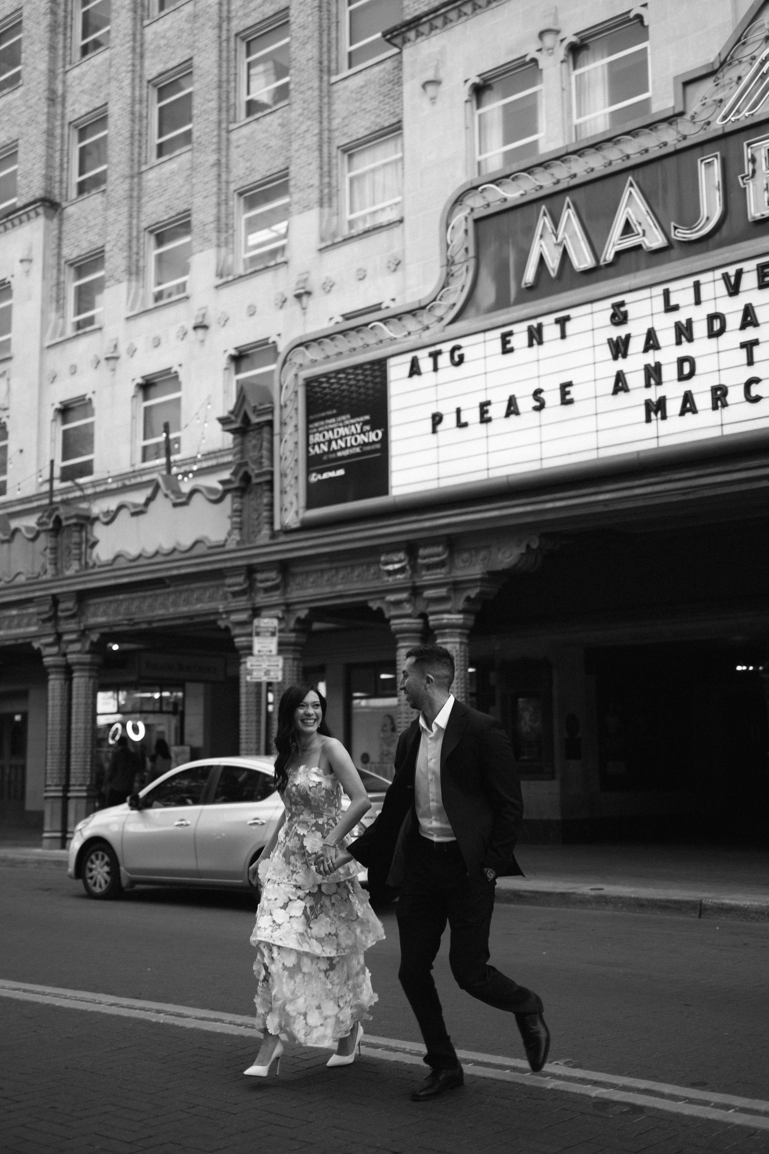 Couple in wedding attire walking hand-in-hand in black and white photo outside Majestic theater. Corpus Christi Wedding Photographer