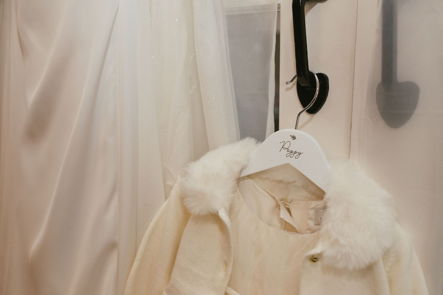 Elegant white wedding gowns being adjusted in a sunlit room.