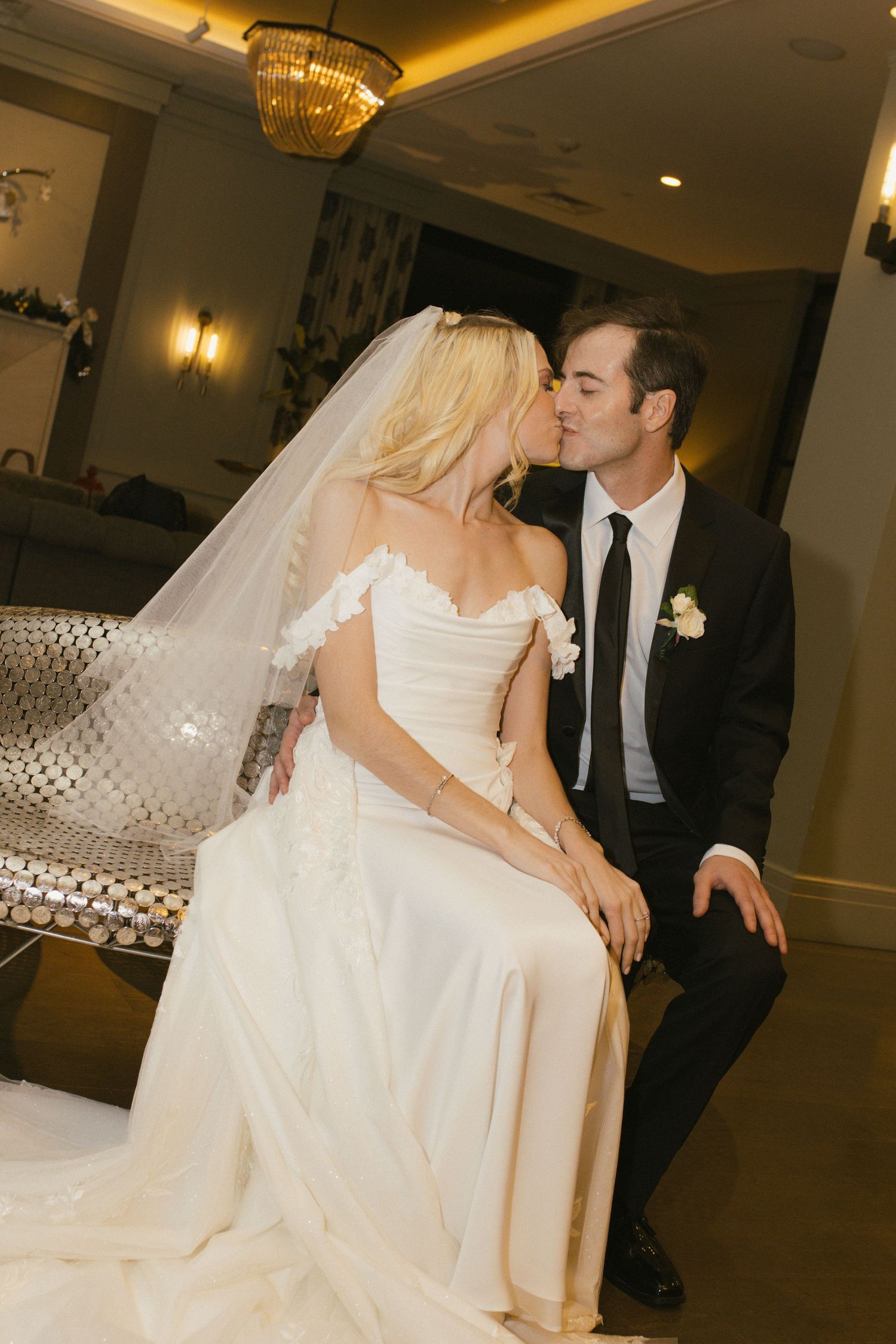 Intimate wedding moment with couple sharing a kiss on elegant seating.