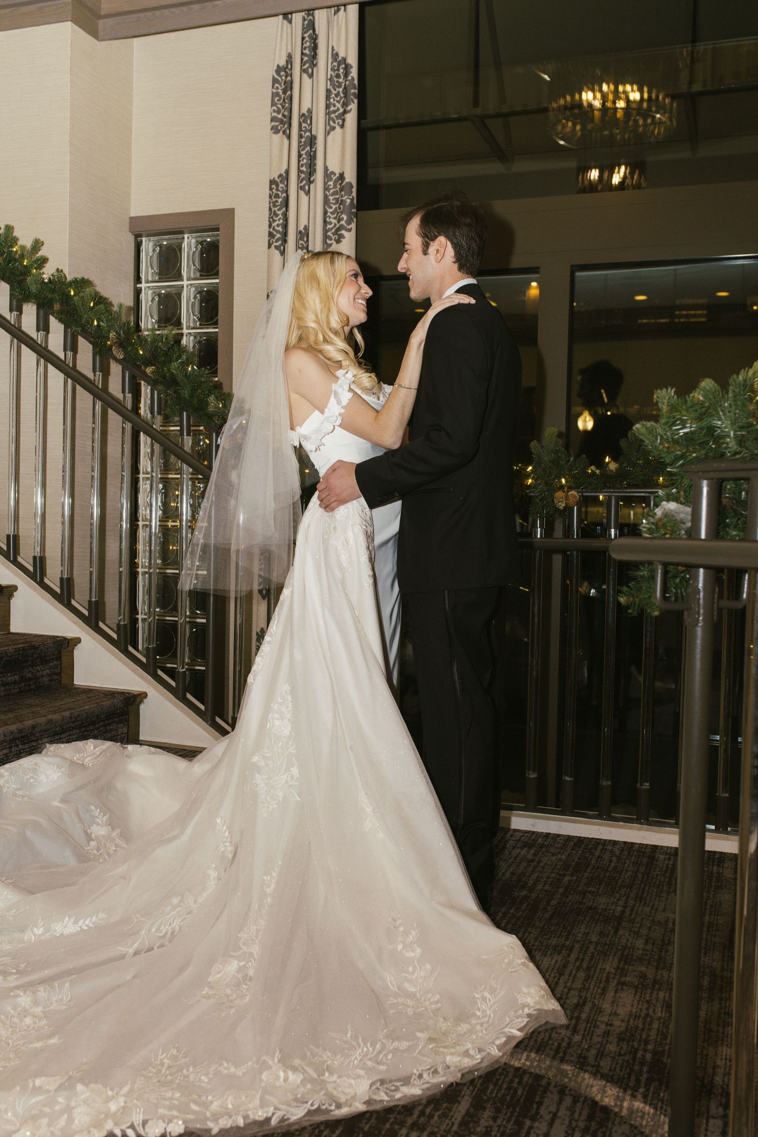 Romantic dance sequence of newlyweds by an ornate staircase with holiday decorations.