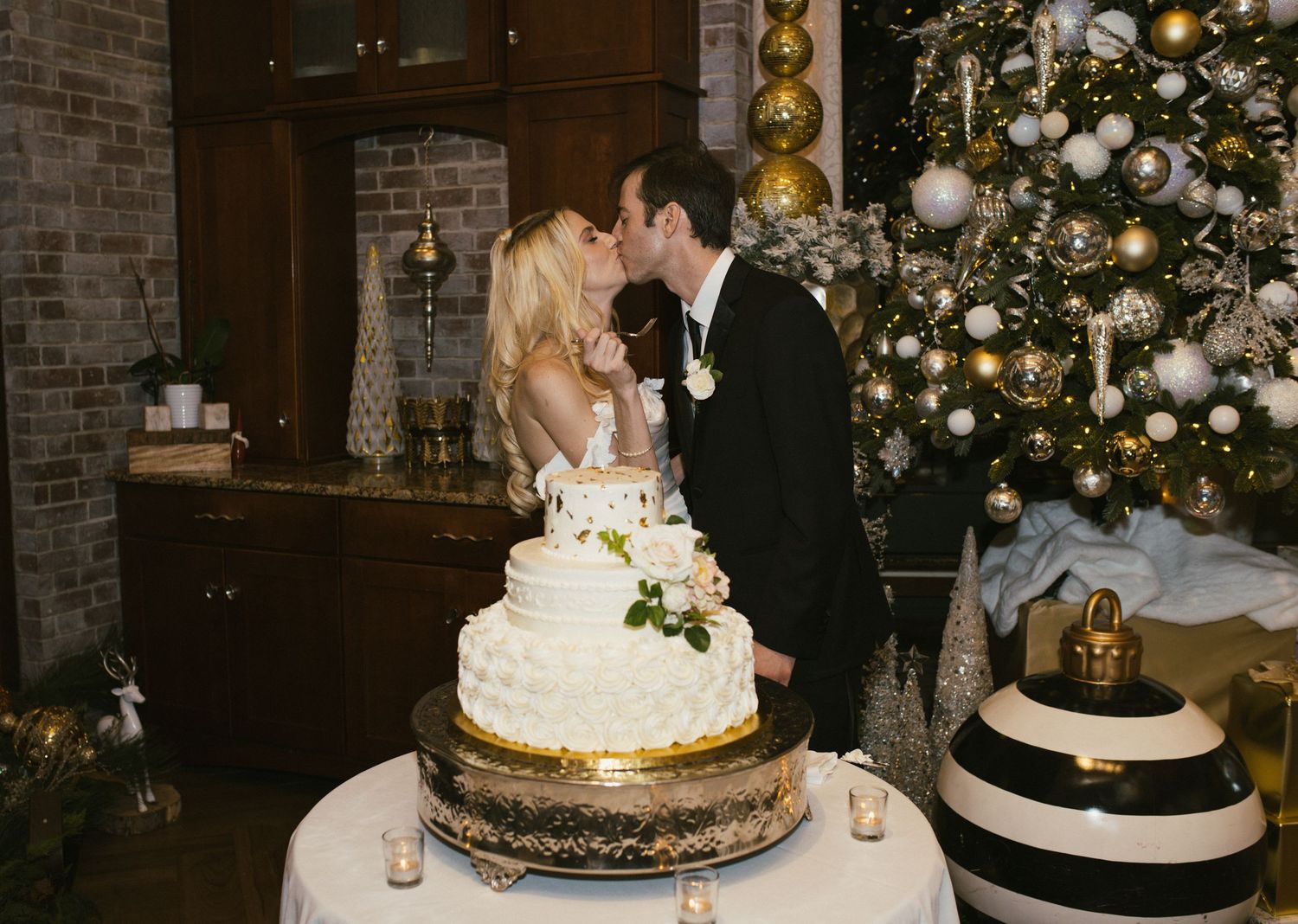 Wedding cake display table with multiple tiers and elegant decorations in a rustic brick venue.