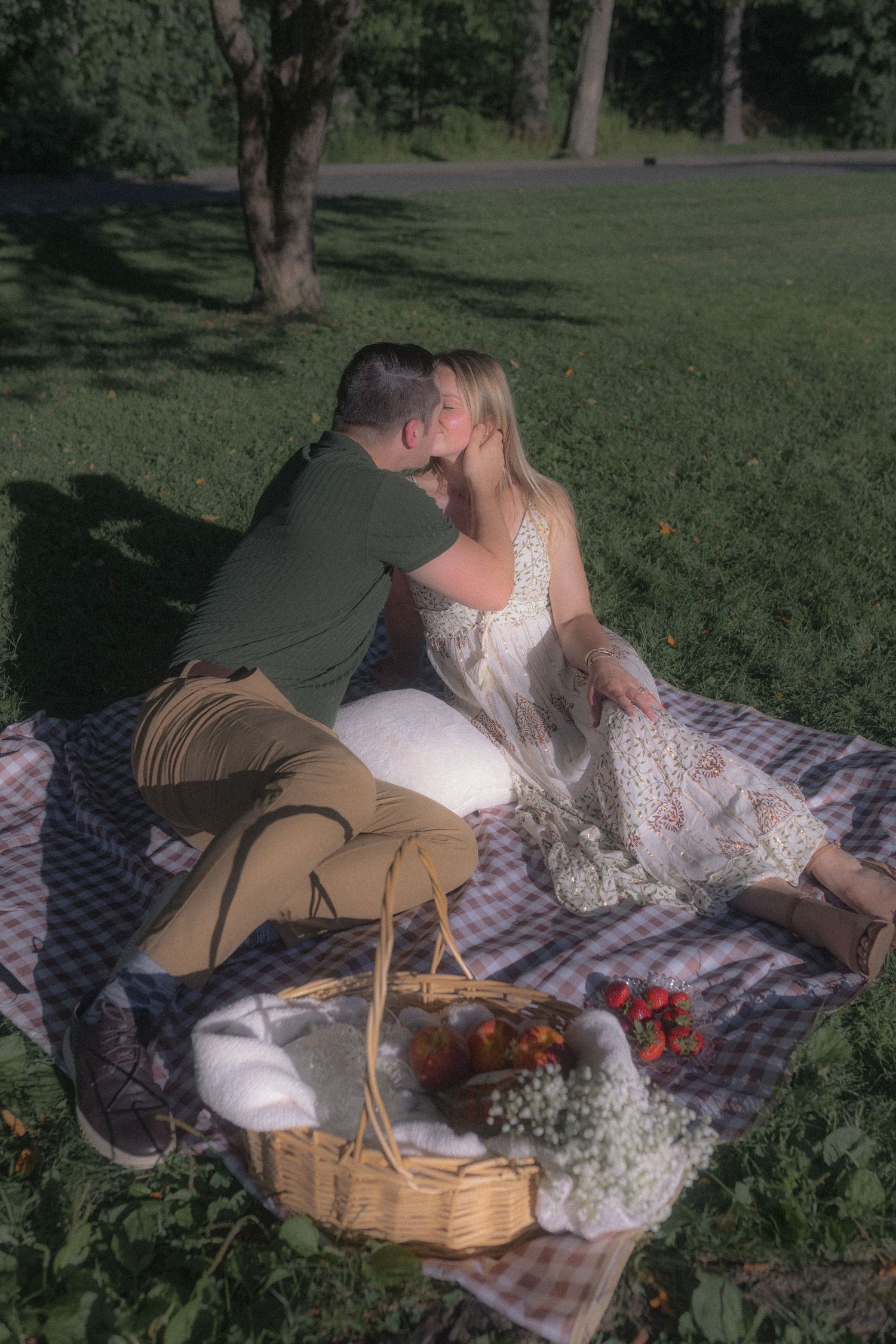 A romantic picnic setup with a woven basket and couple lounging on a checkered blanket.