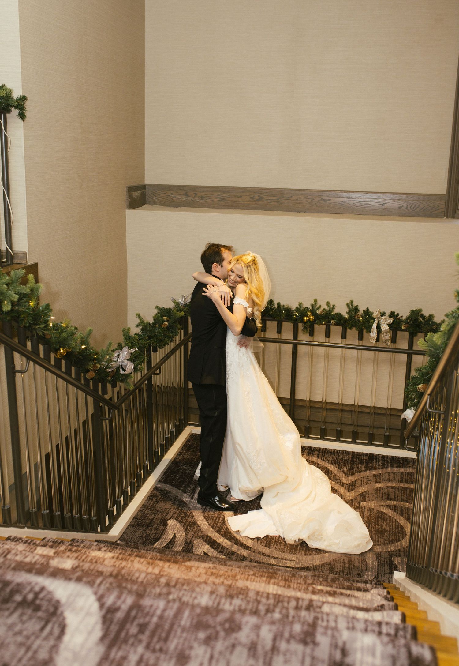 Romantic moment captured on an elegant staircase during wedding celebration.