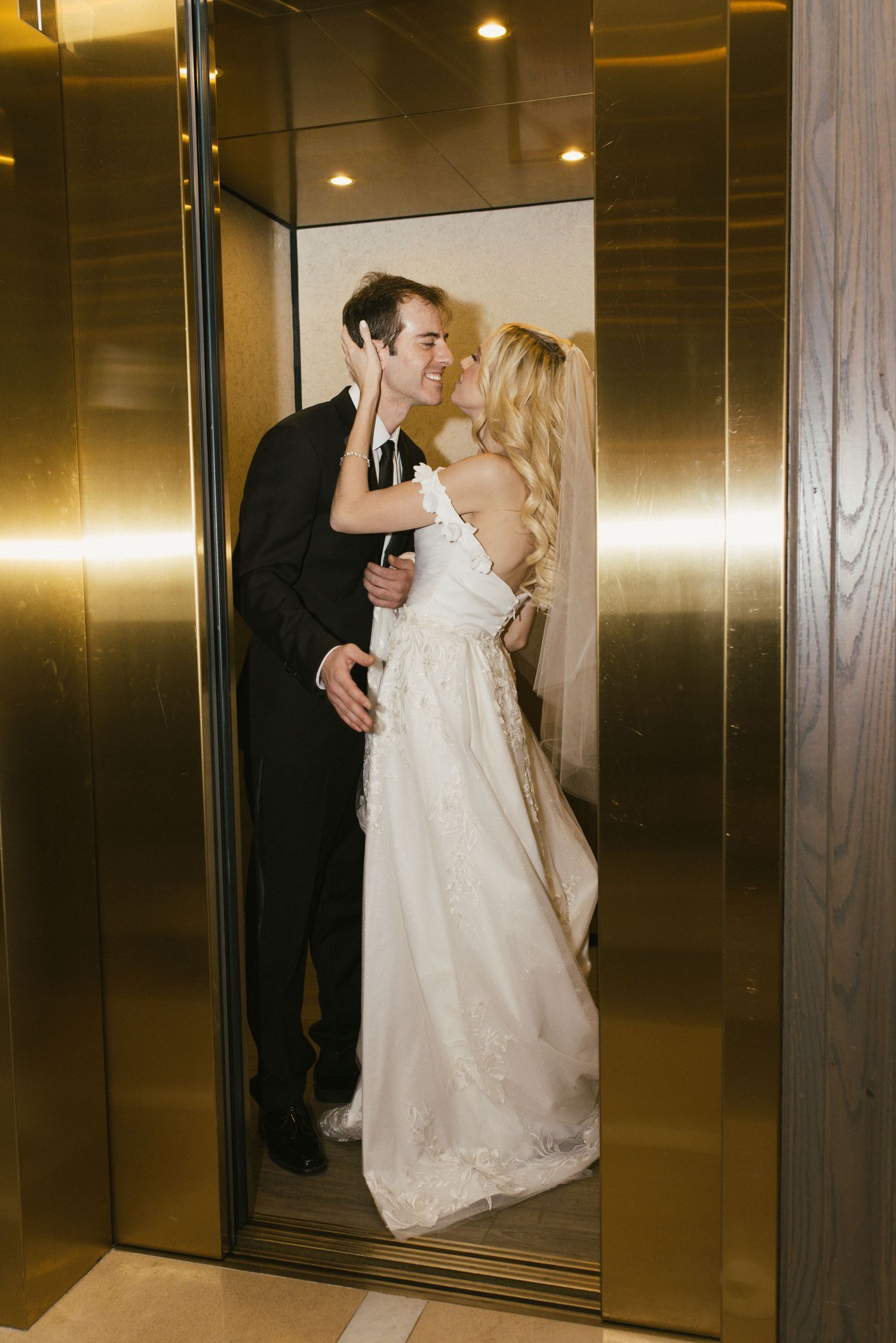 Romantic moment captured in front of a modern elevator with metallic doors.
