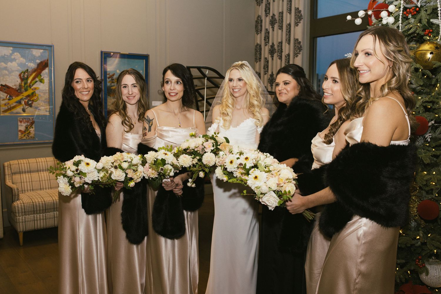 Bridal party holds elegant white floral bouquets while wearing champagne colored gowns.