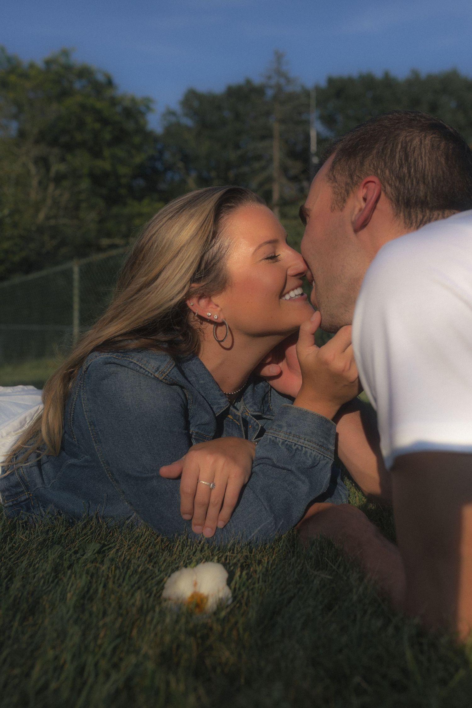 Couple sharing intimate moment in grassy field during sunset photoshoot.