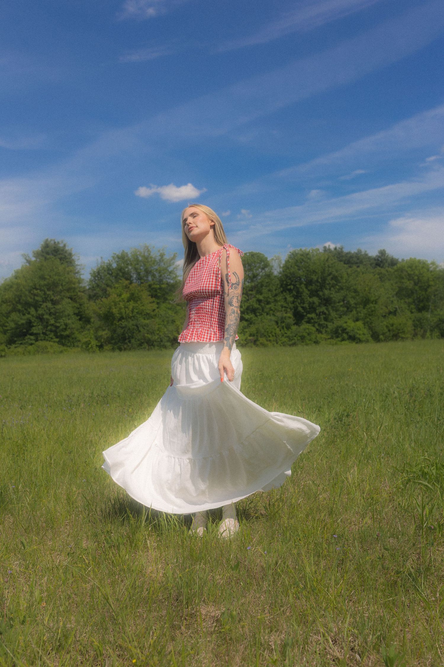Dancing in a white flowing skirt and pink top in a sun-drenched meadow.