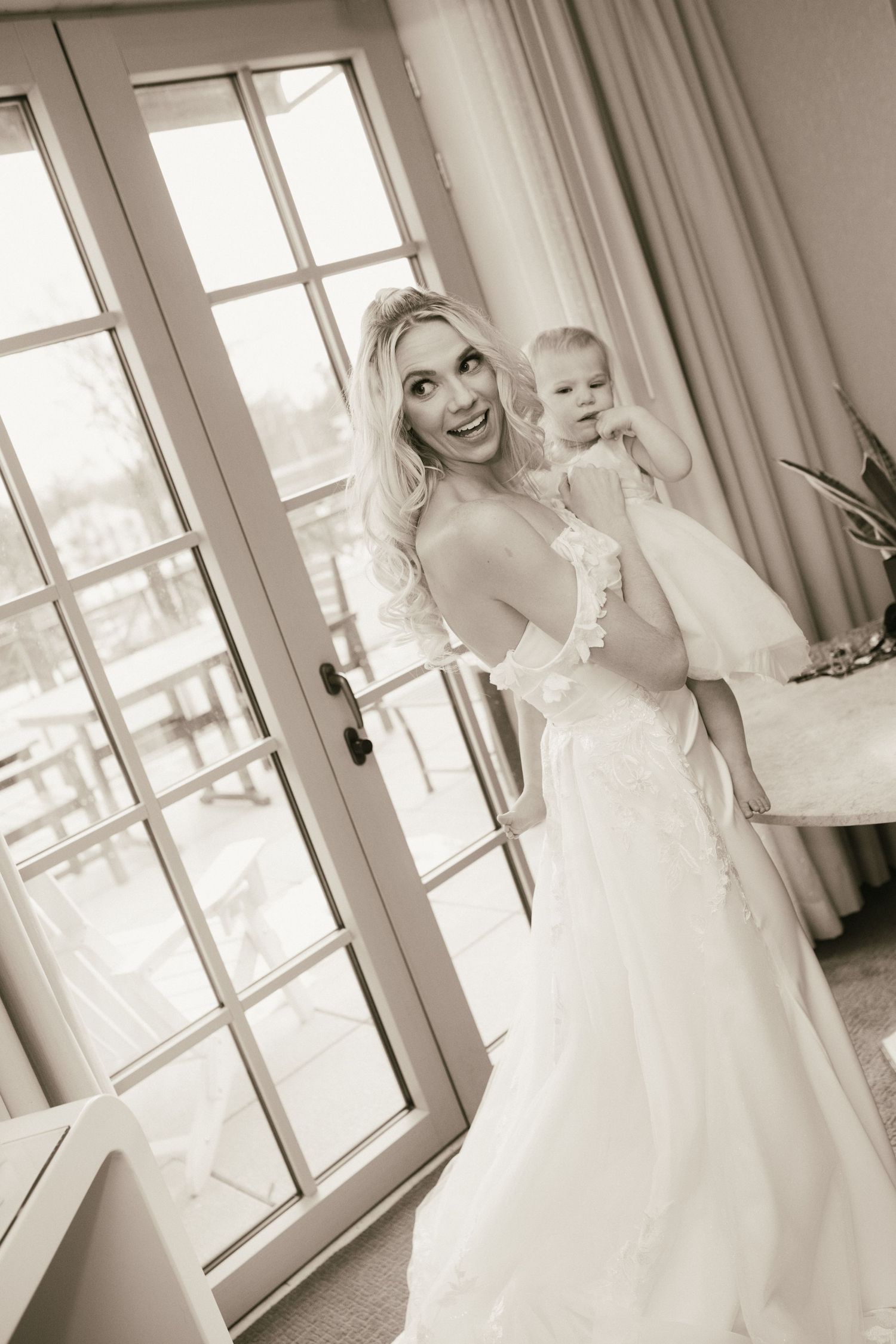 Black and white wedding preparation photos in a bright room with French doors.