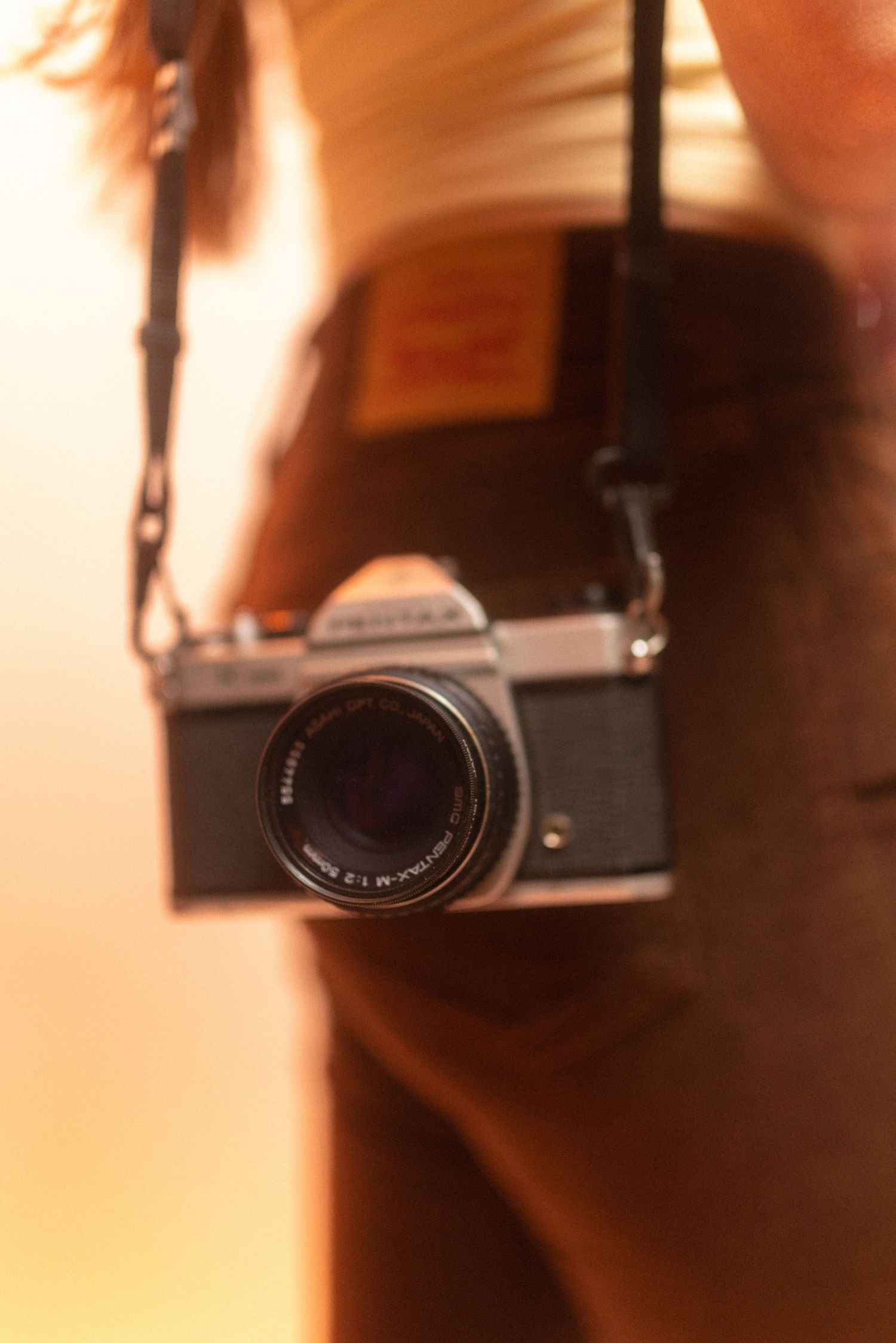 Close-up details of a vintage camera lens and body in warm lighting.
