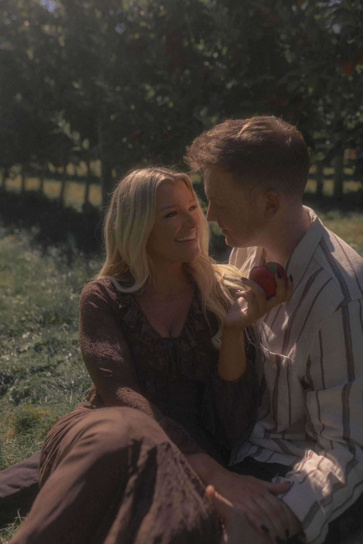 A romantic outdoor portrait of a couple sharing an intimate moment in a sunlit garden setting.