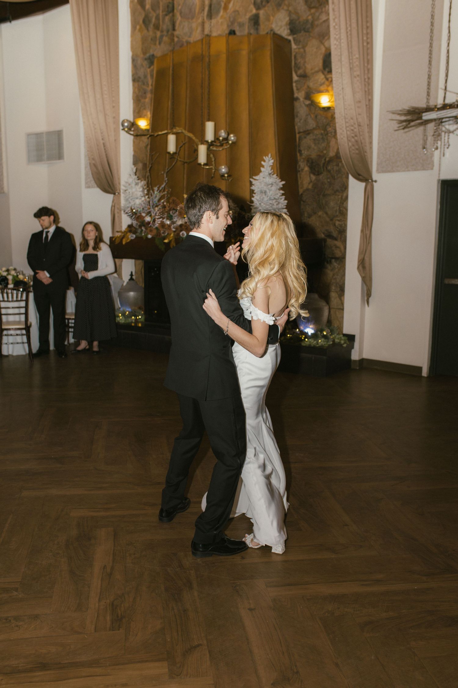 Couples slow dancing on a dark hardwood floor at an elegant wedding reception.