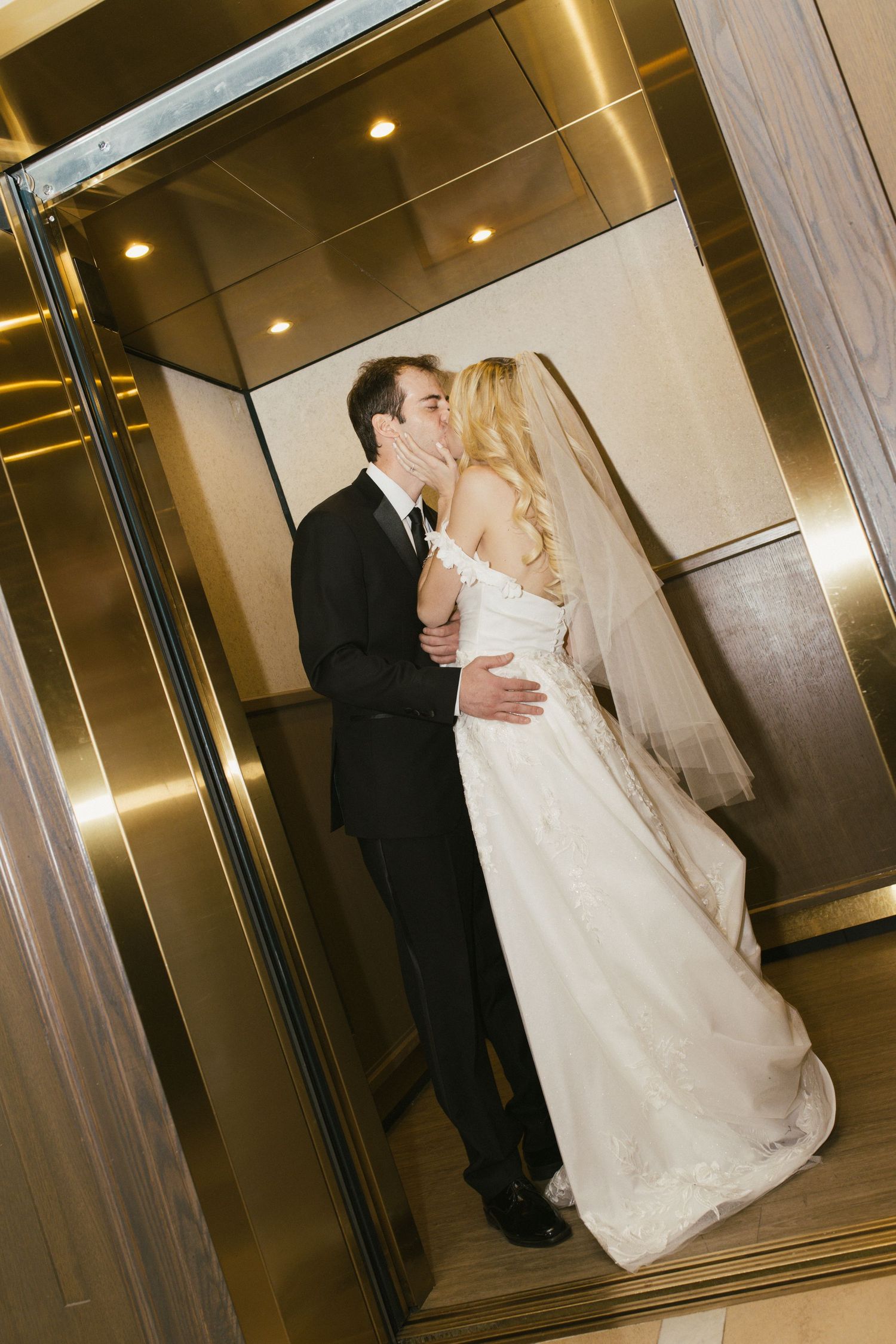 Wedding couple dancing and embracing in a modern elevator setting.