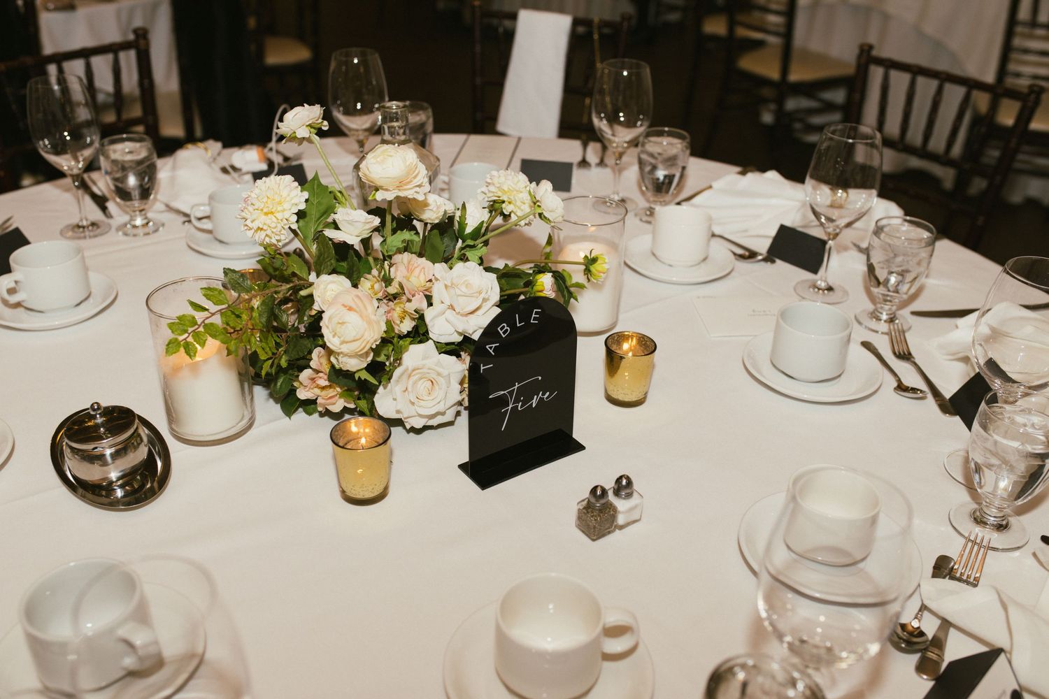 Elegant table settings with glassware and floral centerpieces at a wedding reception.