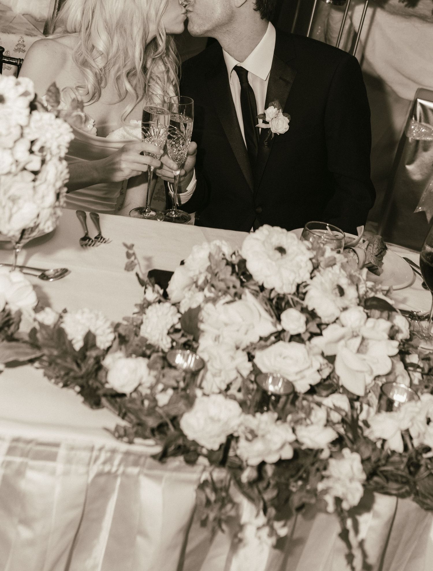 Black and white photo of wedding reception table with elaborate floral centerpieces.