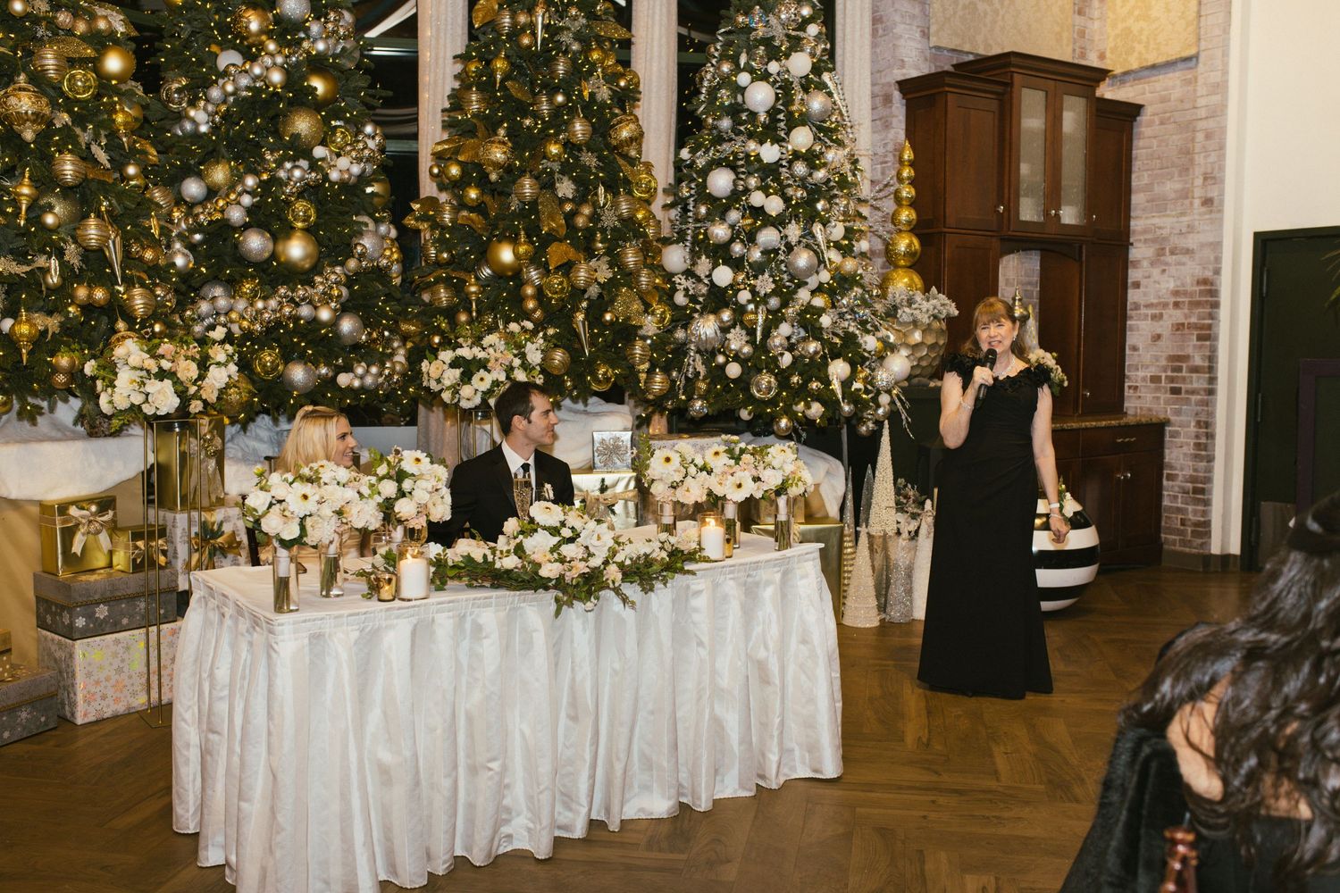 Wedding reception venue decorated with twinkling lights and white floral arrangements along elegant dining tables.