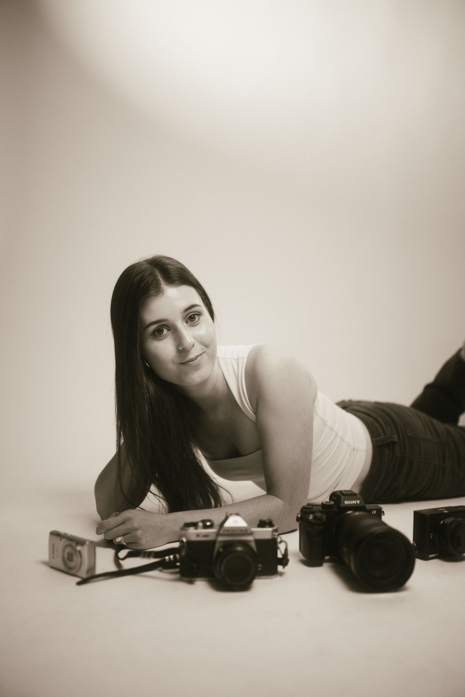 Black and white portrait series showing a woman lying down with a vintage camera in artistic poses.