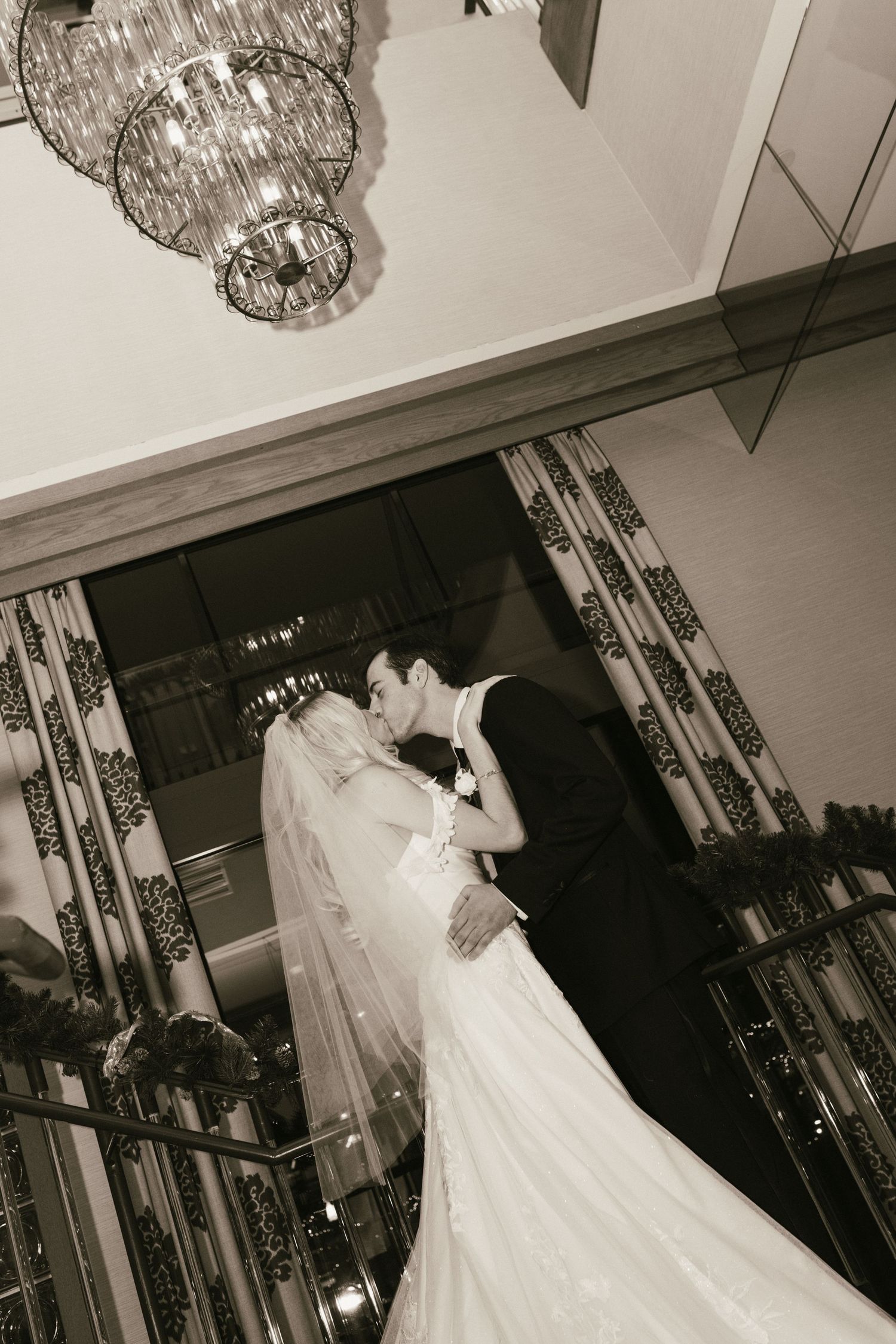 Wedding couple dancing under crystal chandelier in black and white photography.
