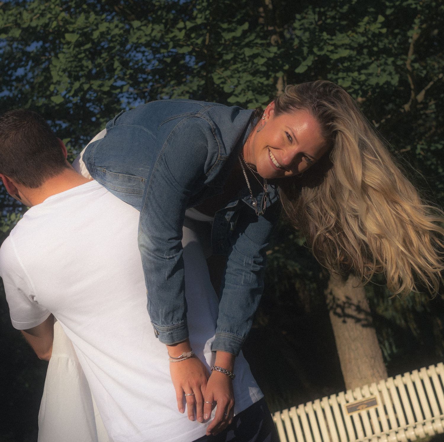 Romantic couple playfully interacting on a white bench outdoors.