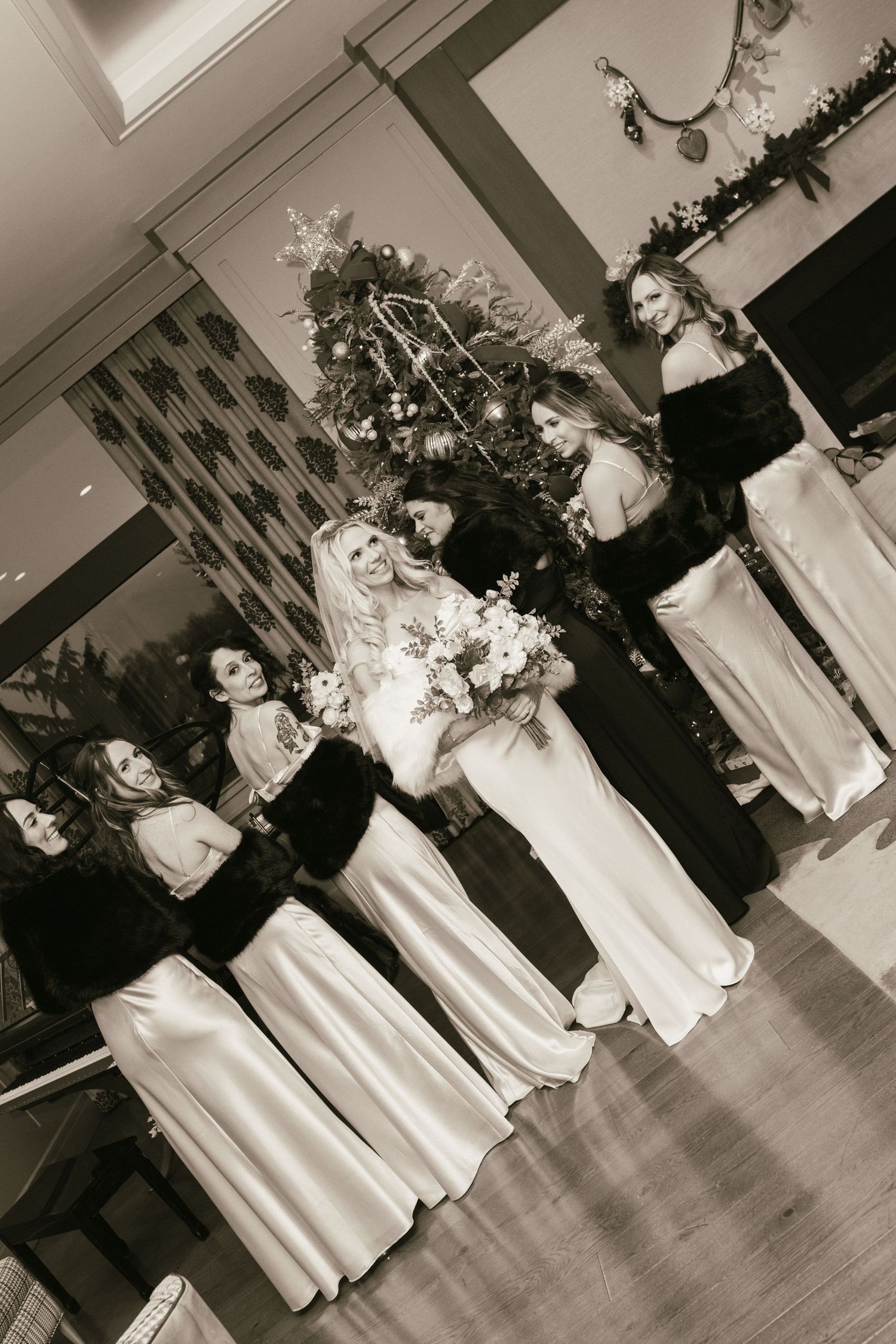 A wedding party in black and white poses near a decorated Christmas tree.