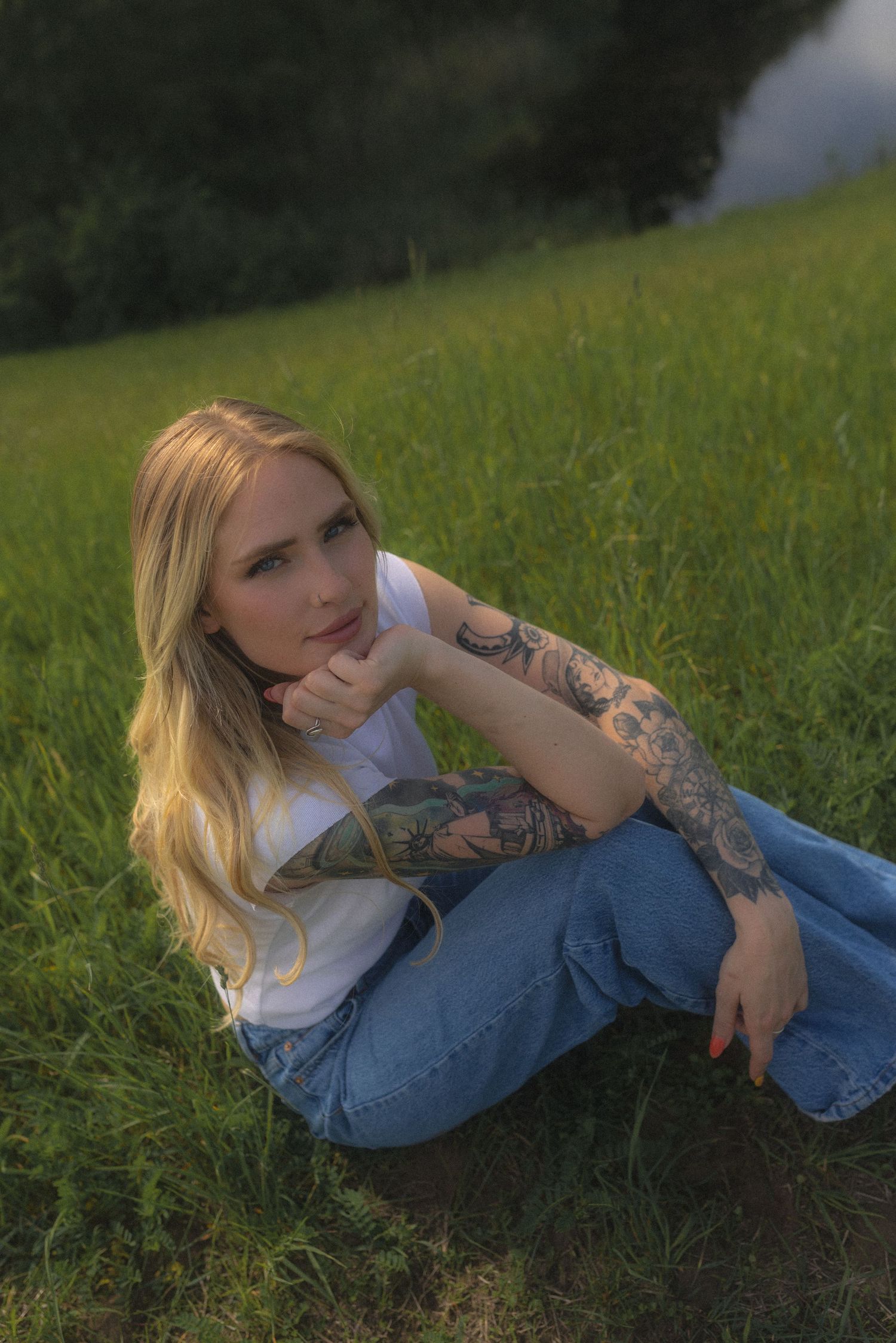 Artistic portrait of someone reclining in denim against green grass.