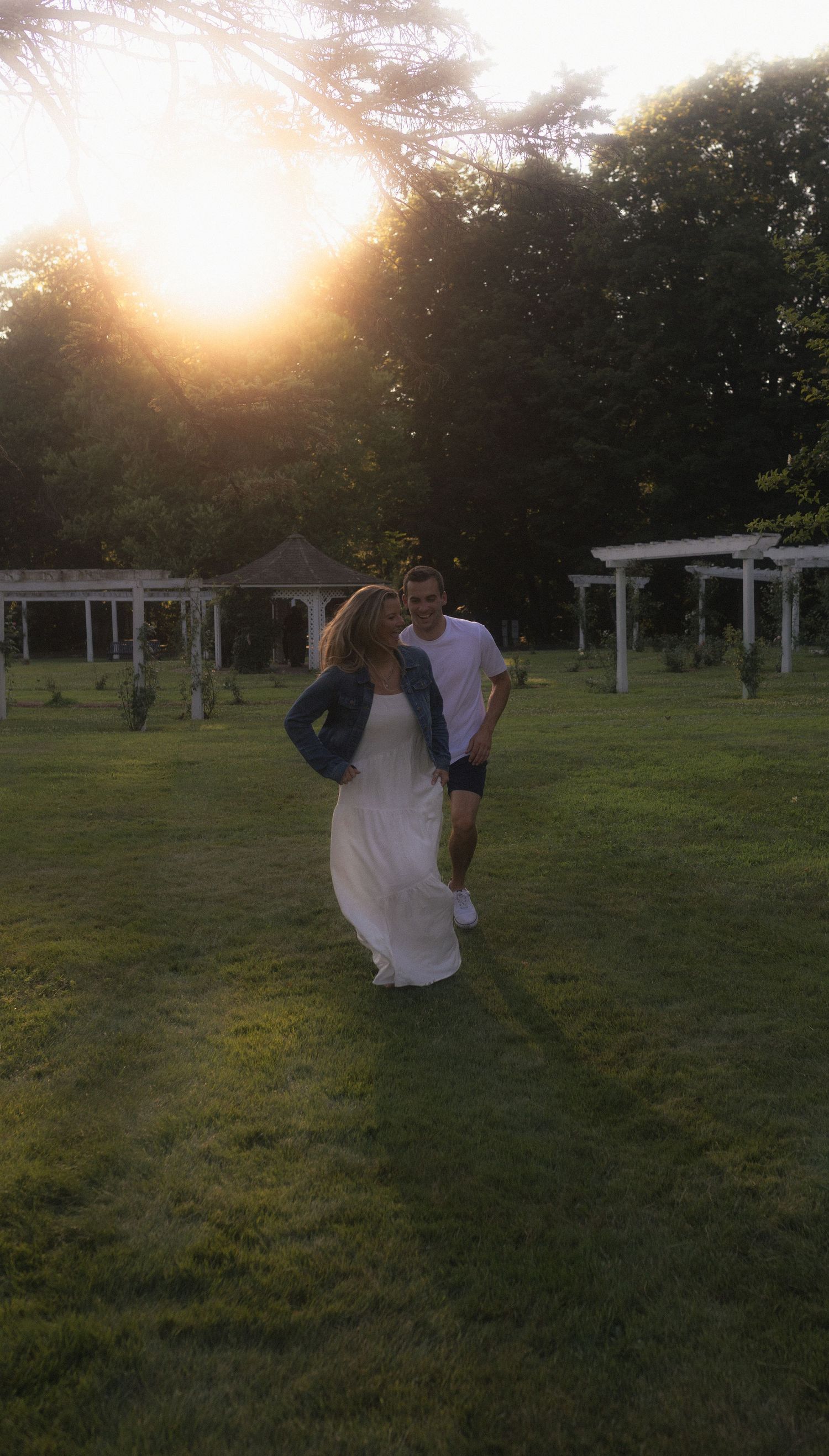 Silhouetted couple dancing in golden sunset light on grassy field.