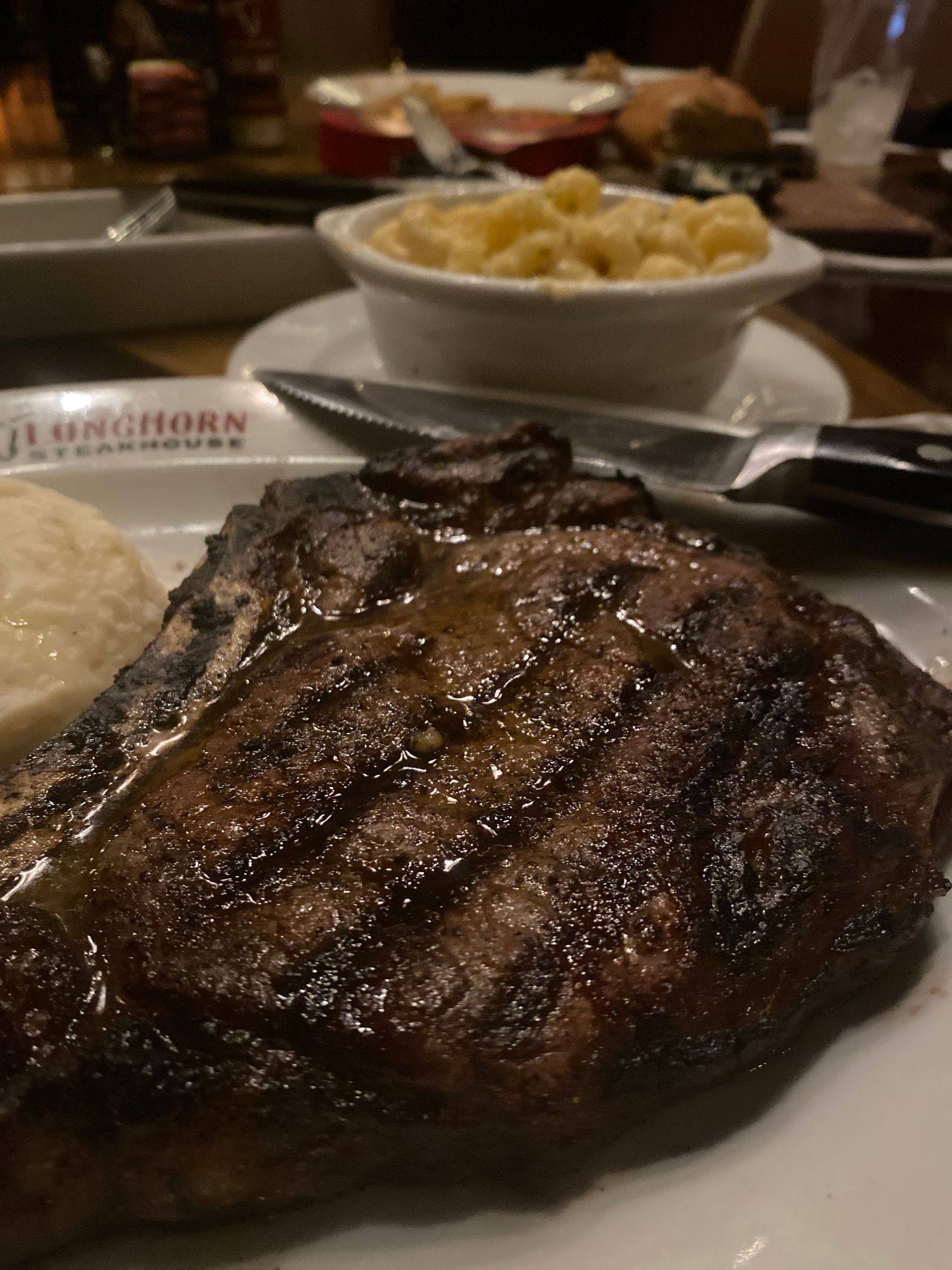 Grilled steak with a dark charred crust served on a white plate at an upscale restaurant.