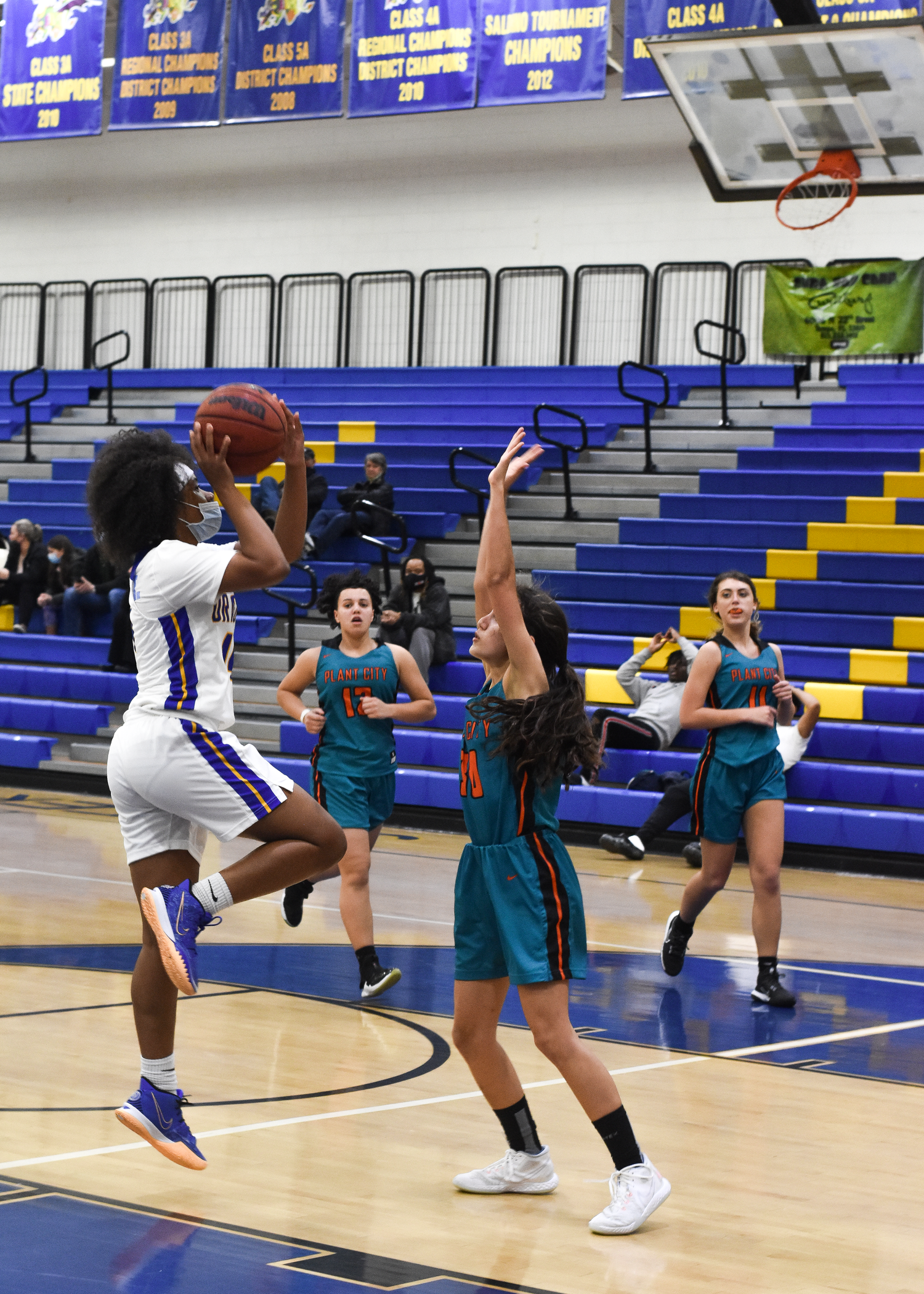 Players in white and teal uniforms compete for possession during a basketball game.