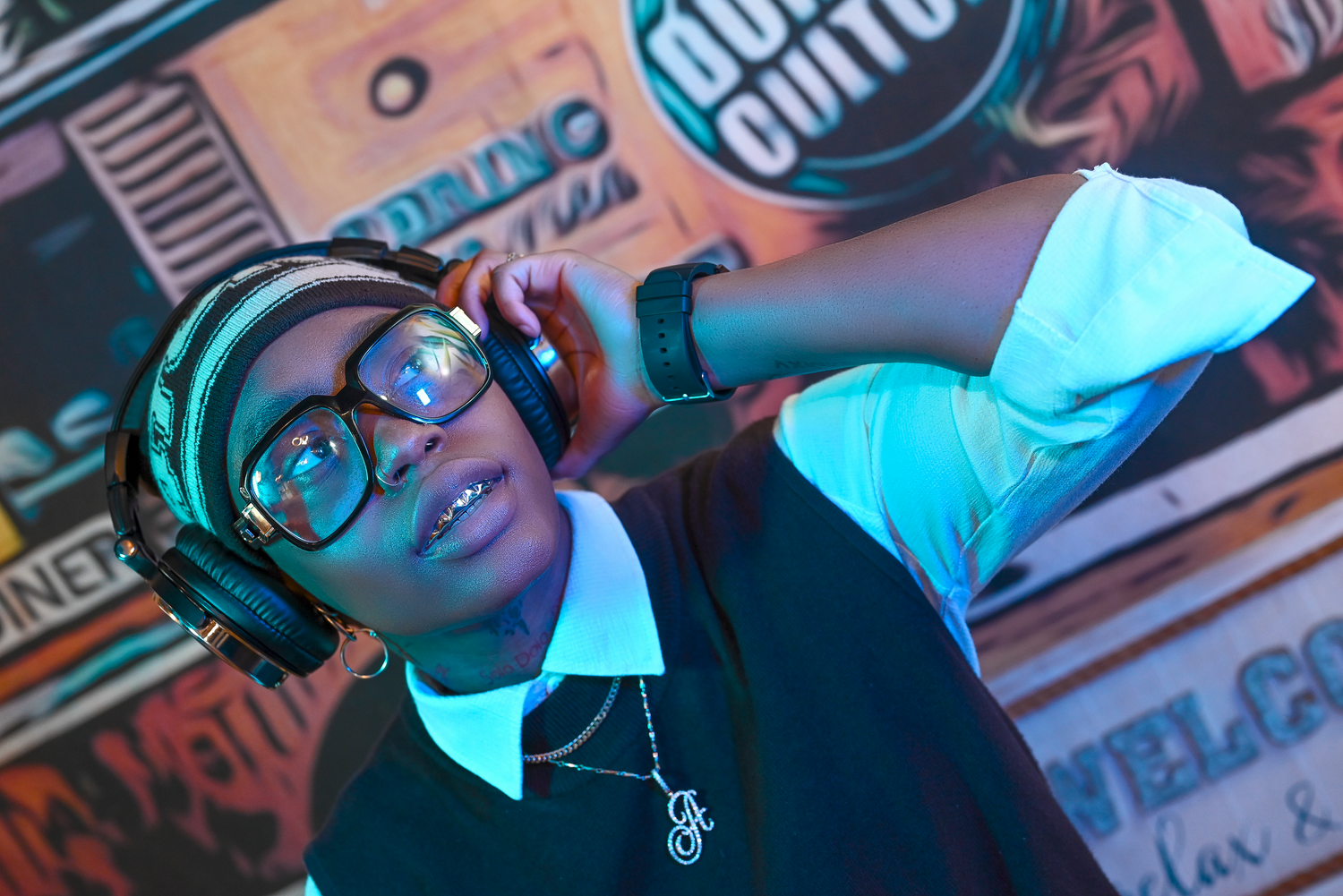 DJ performance with headphones against vibrant branded wall art.