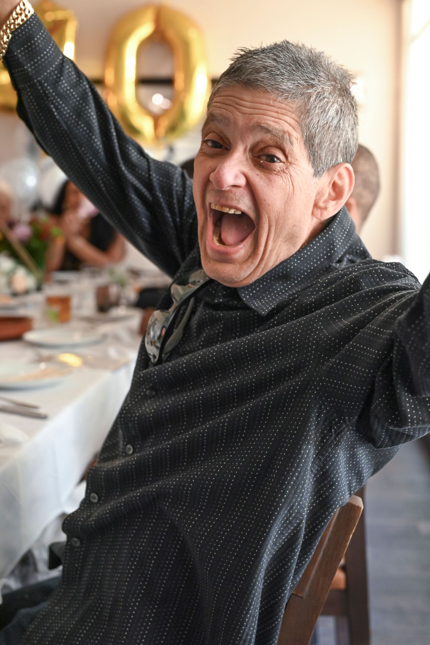 Person in a black sweater expressing joy with raised arms and animated expressions.