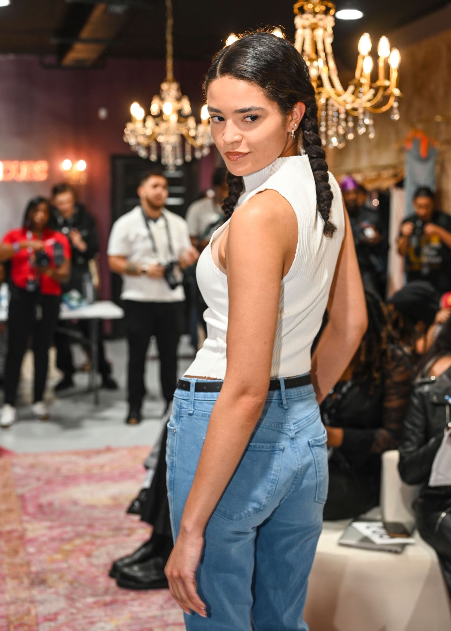 Fashion show featuring models in minimalist white tops and denim on an industrial-style runway.