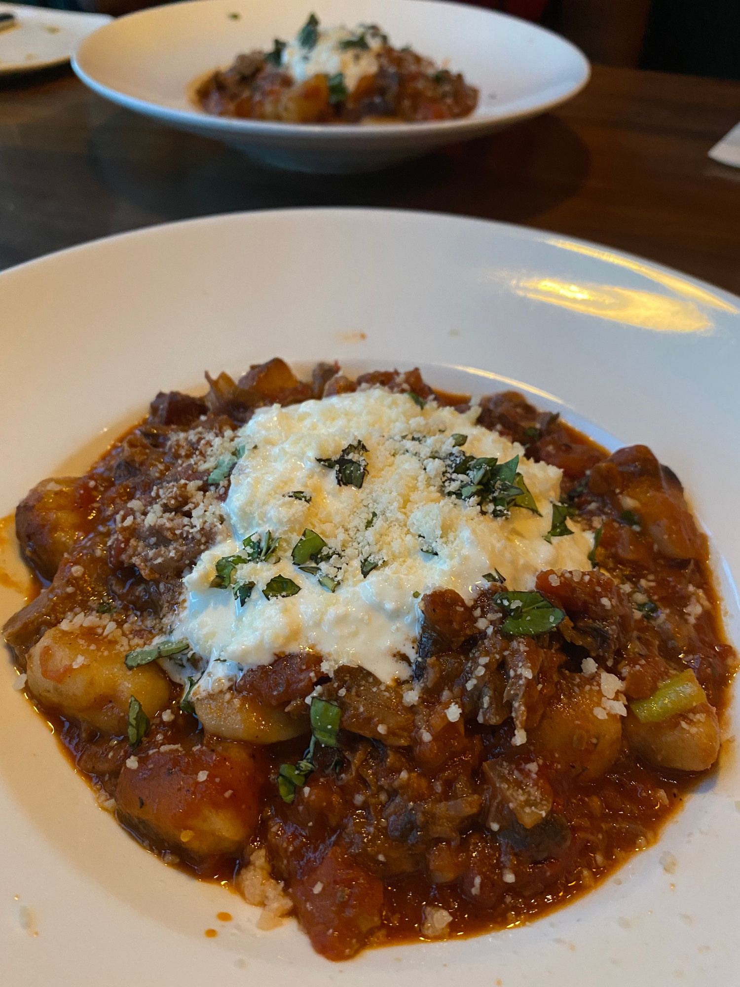 Hearty gnocchi in a rich meat sauce topped with melted cheese and fresh herbs.