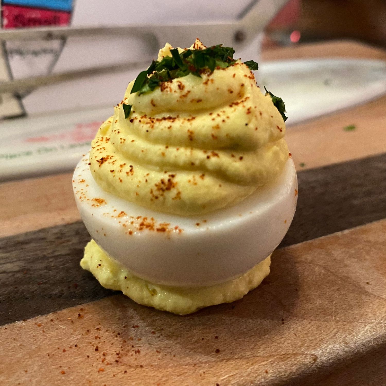 Deviled eggs garnished with herbs and spices arranged in a row on a wooden surface.