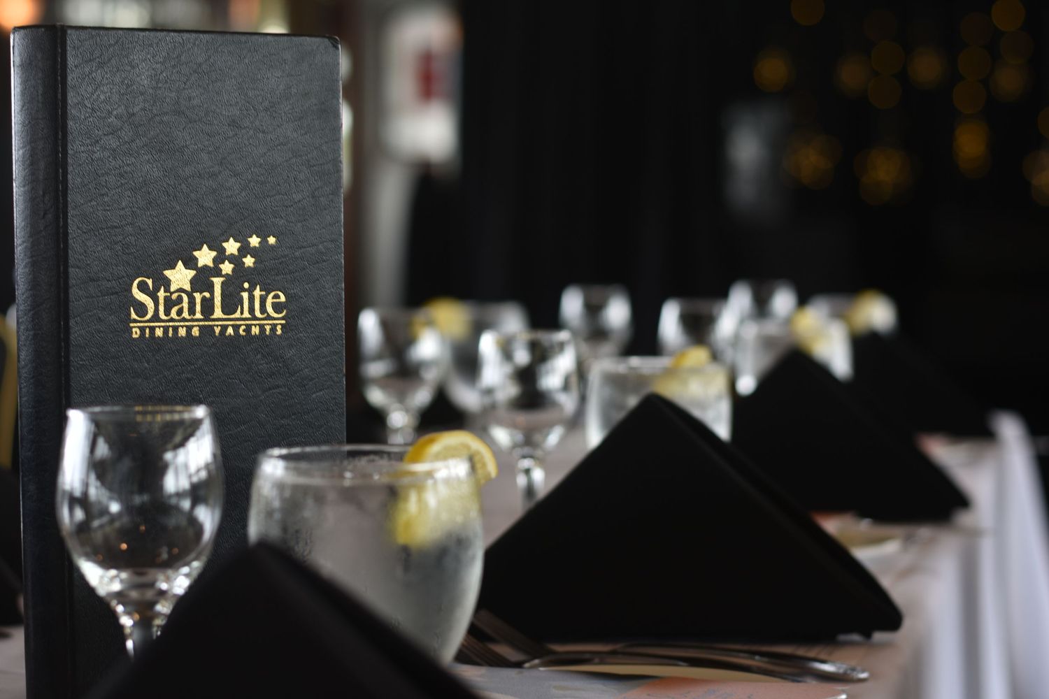StarLite Dining Yacht menu displayed on elegantly set table with black napkins and wine glasses.