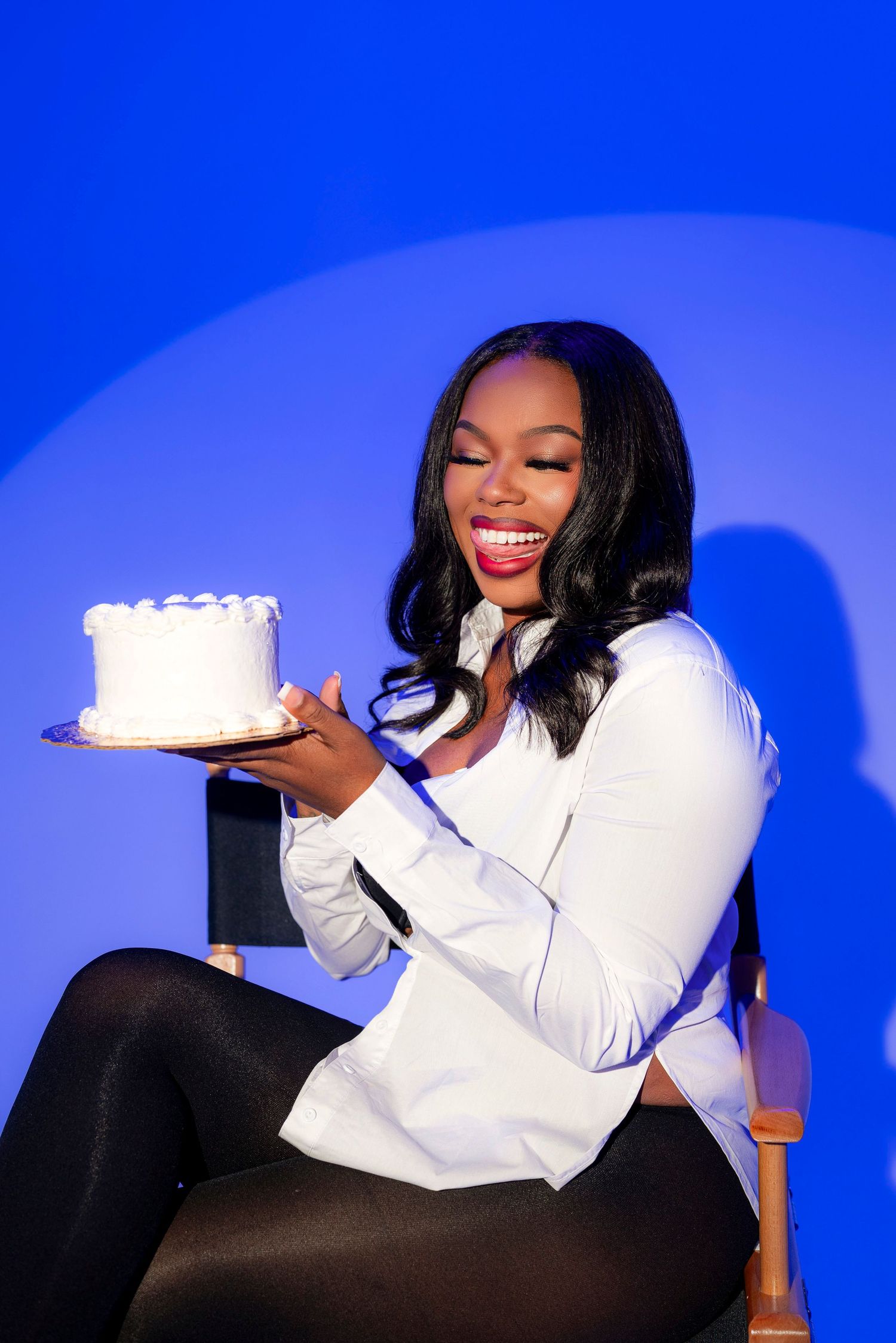 Woman in white shirt holding cake against blue background in playful photo sequence.