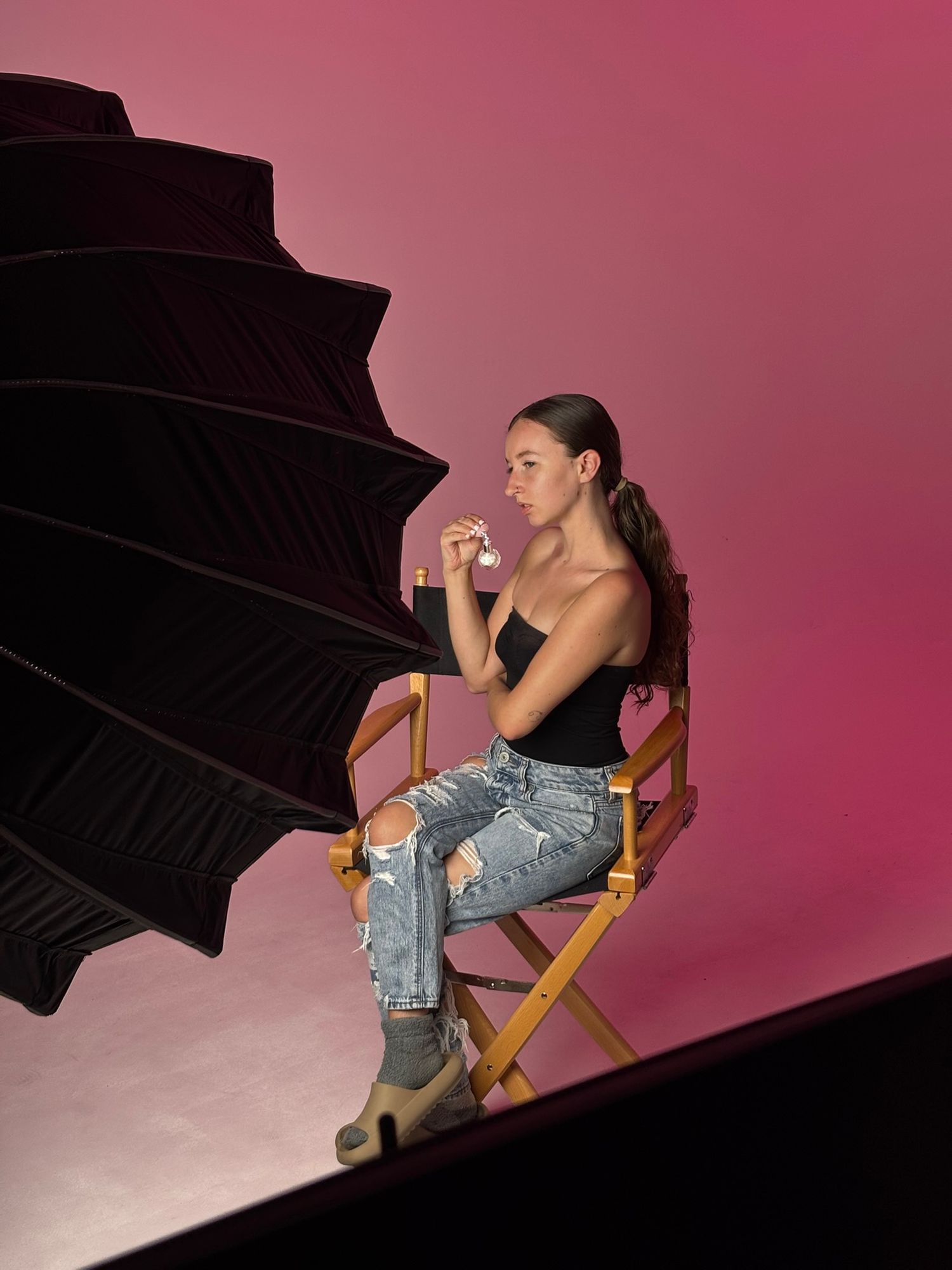 Fashion photography shoot setup with pink backdrop and studio lighting.