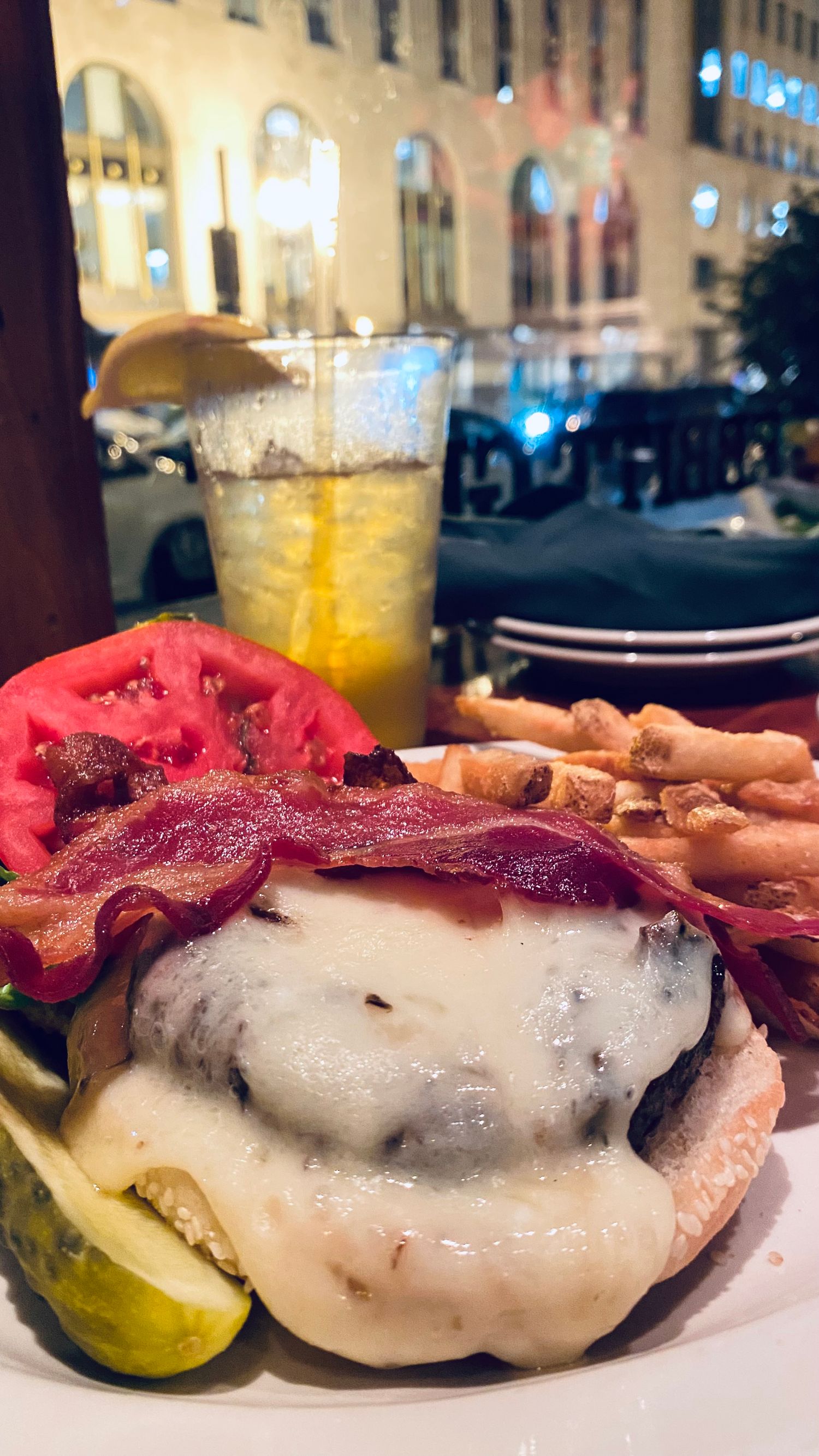 Juicy burger topped with melted cheese and crispy bacon served with pickles on the side.
