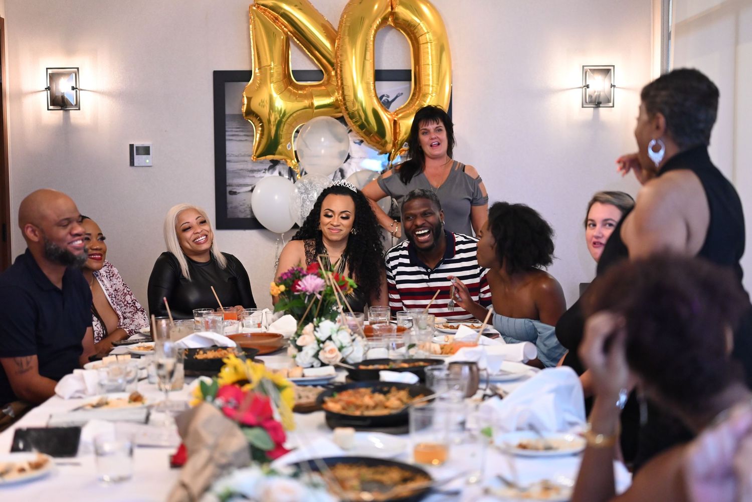 Celebratory dinner party with gold balloon decorations and elegant table settings.