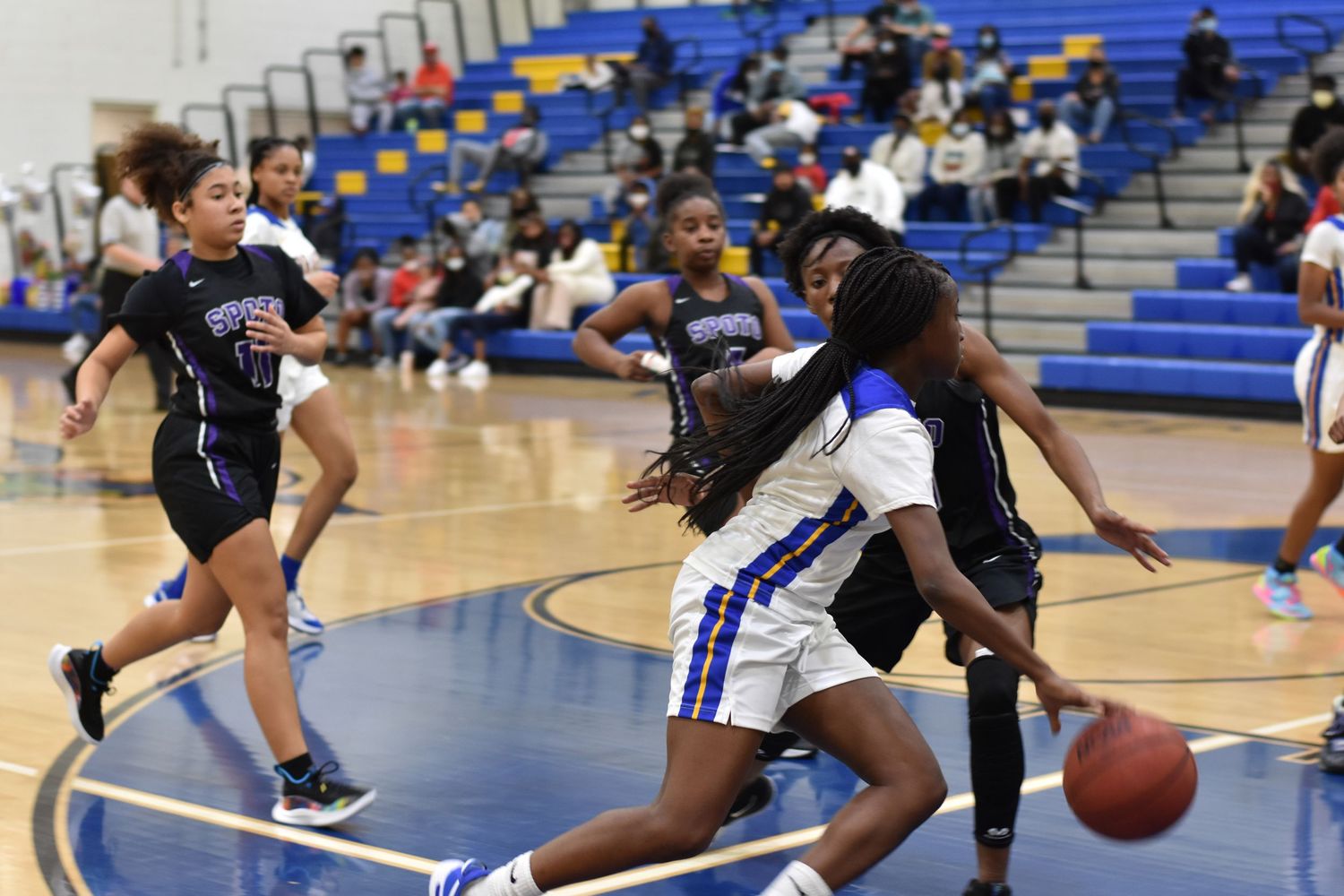 Basketball players dribbling and defending during an indoor game.