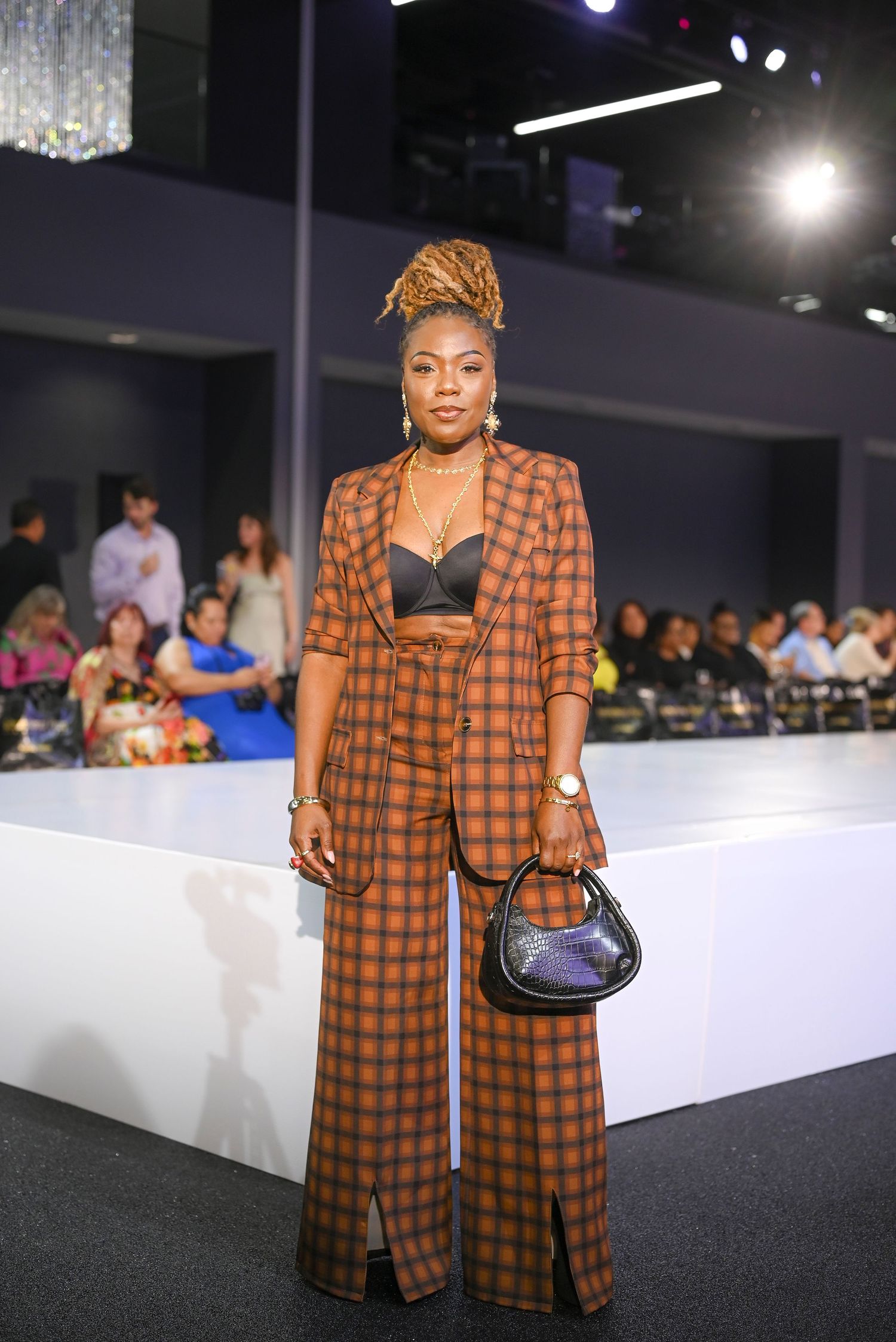 Person modeling orange plaid outfit on runway at fashion event.