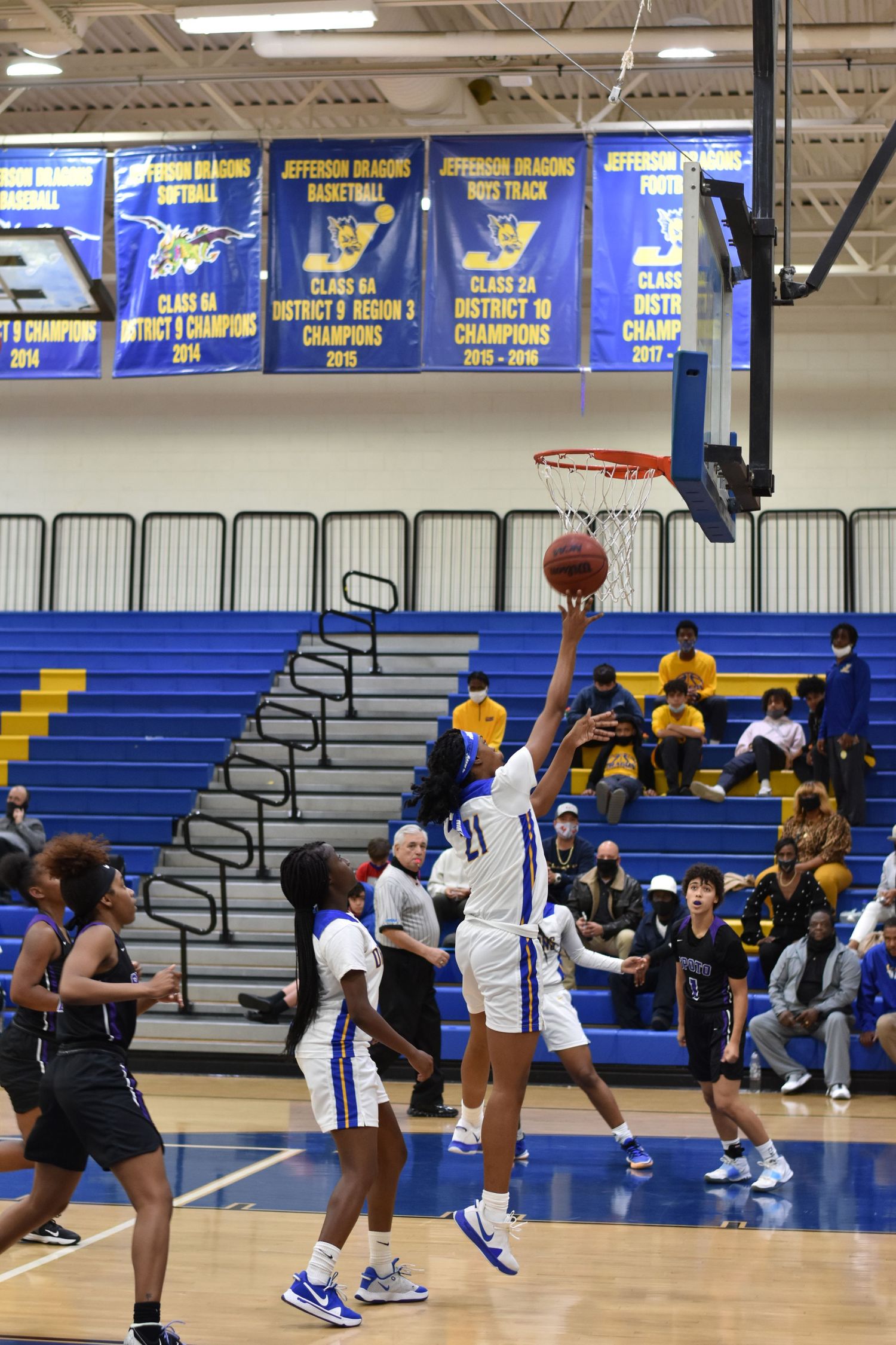 Basketball game in progress with players from opposing teams competing under the hoop.