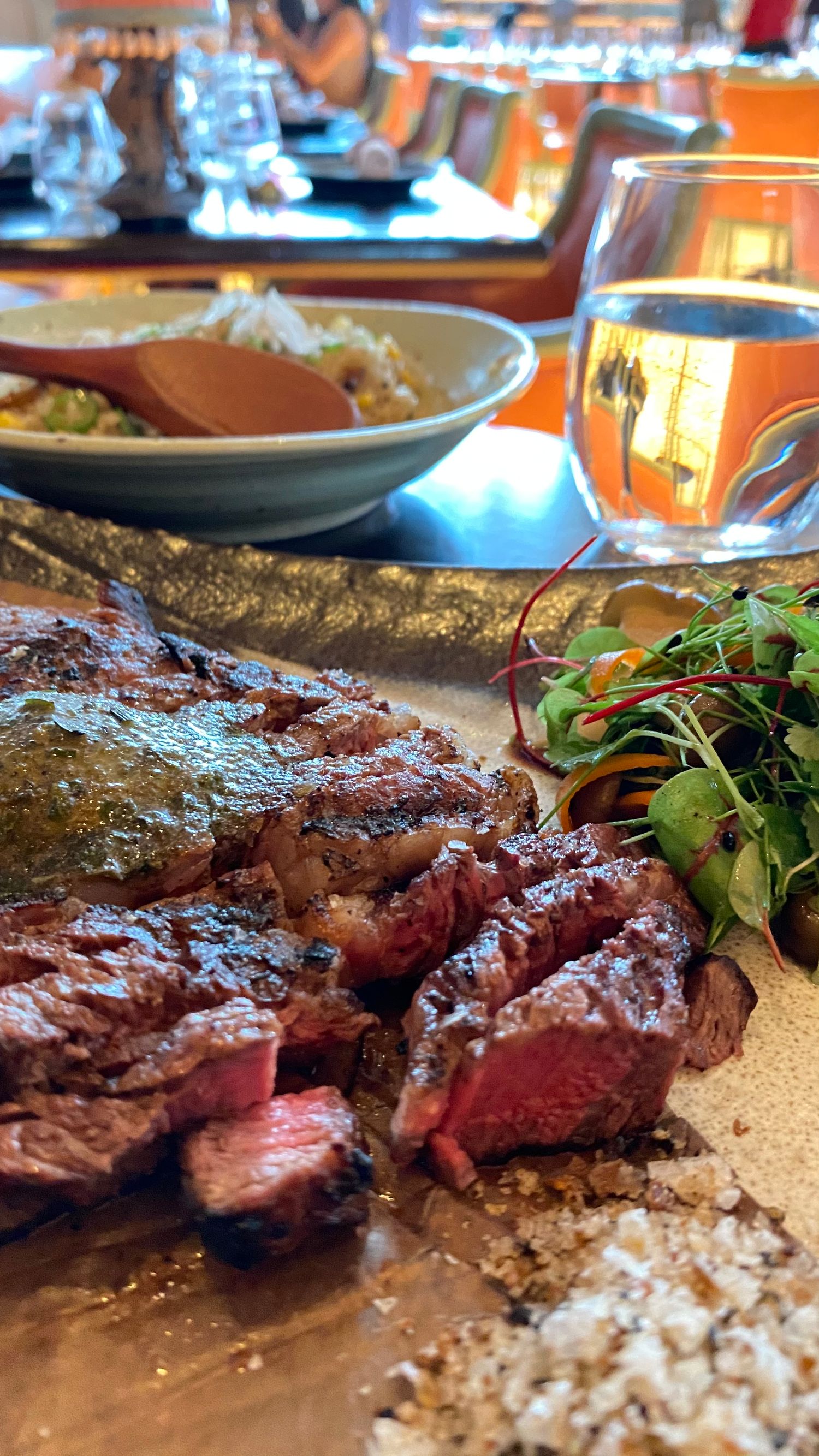 Sliced medium-rare steak served with a fresh green salad and rice on the side.