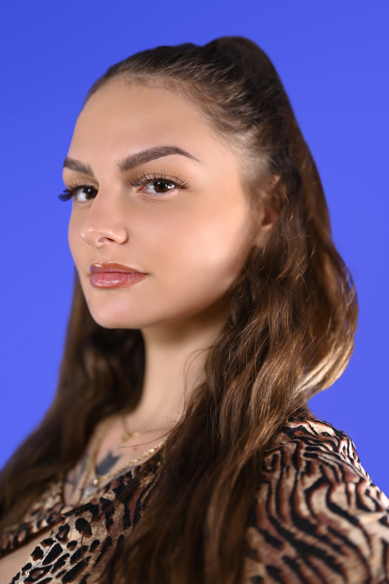 Fashion portrait with animal print top against vibrant blue backdrop.
